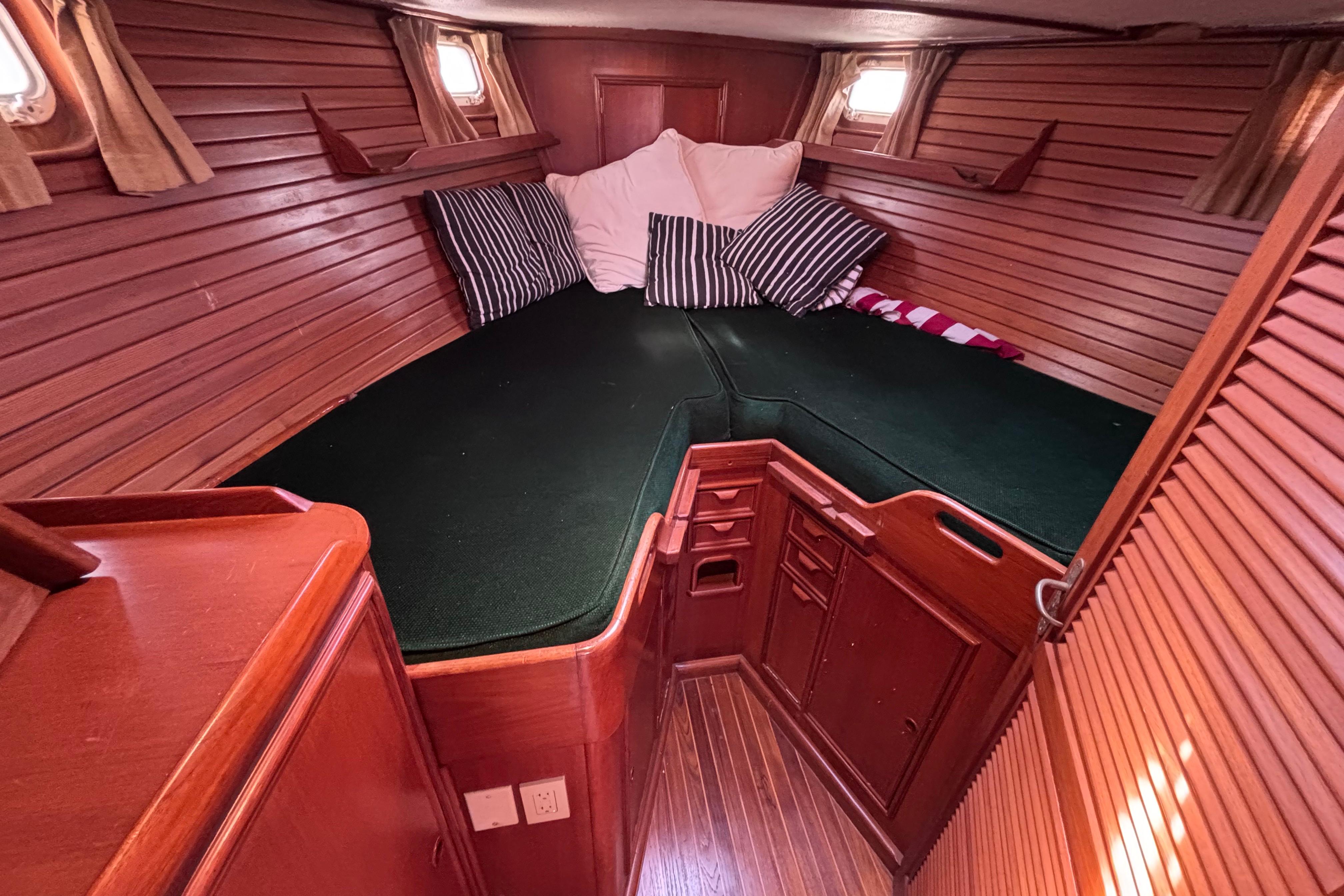 Cozy cabin interior of 1978 Swift 33 sailboat with wooden paneling and green bedding.