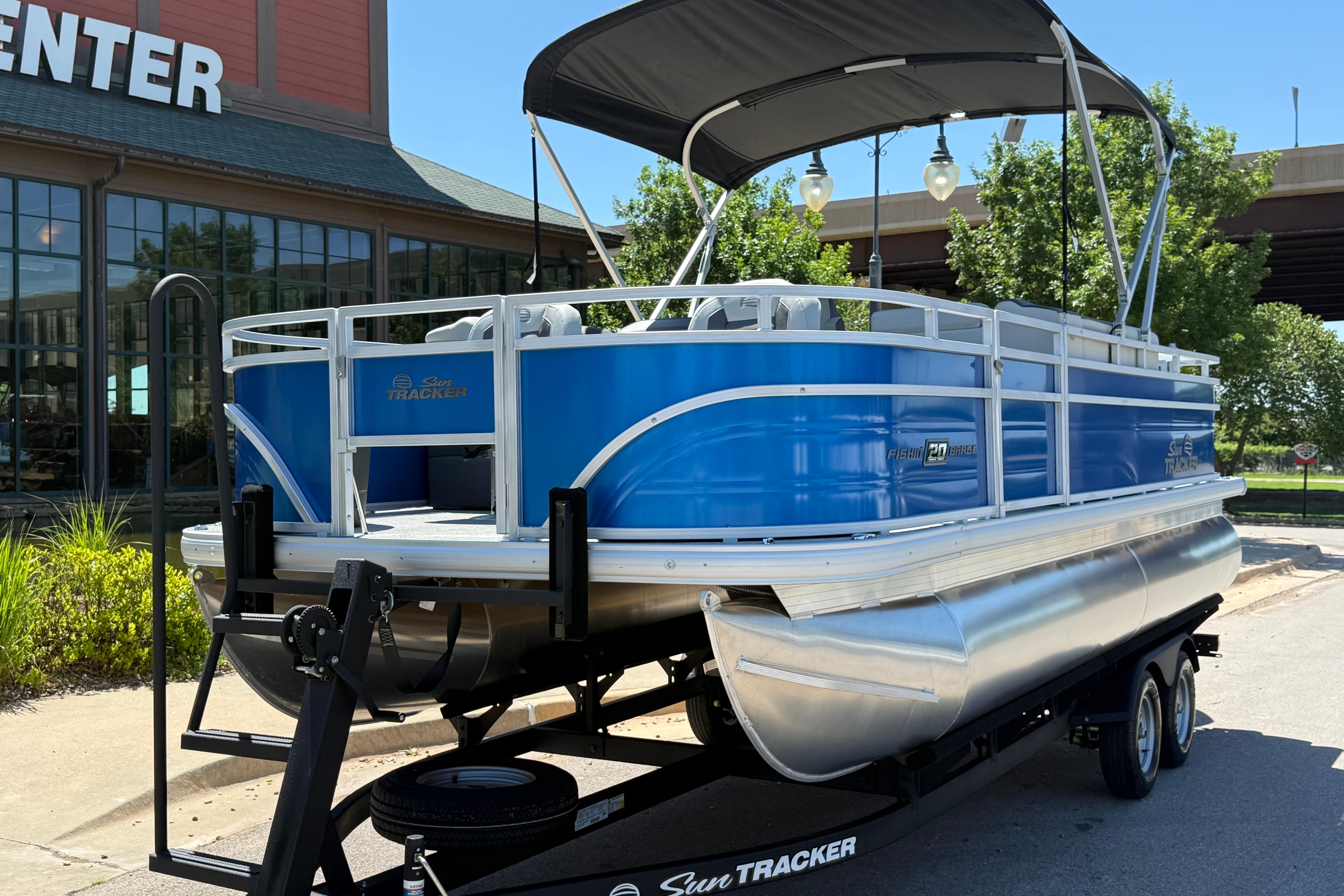 2026 Sun Tracker Fishin' Barge 20 DLX pontoon boat on trailer, parked outdoors.