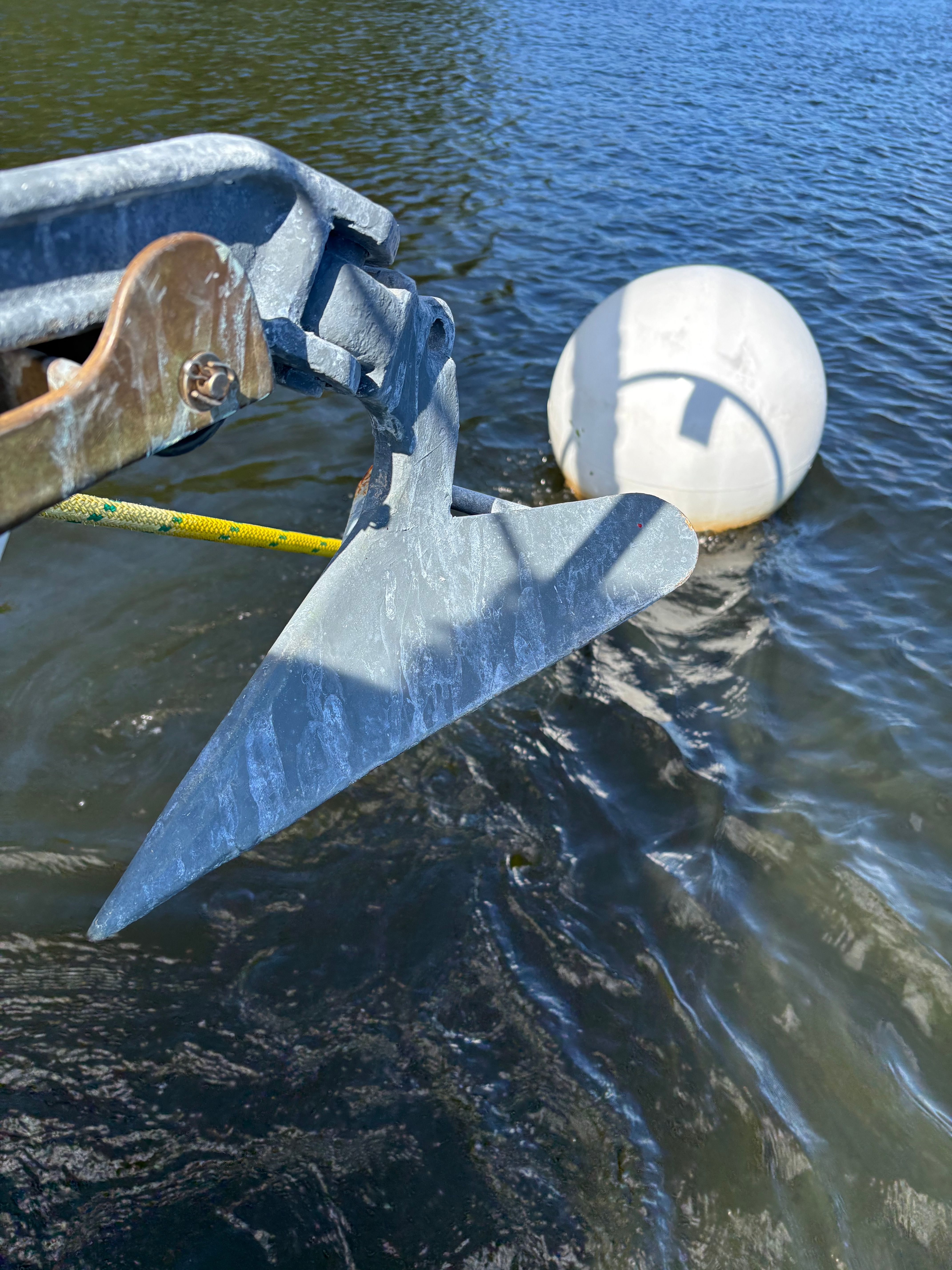 Anchor of a Cape Dory 26 boat near a buoy in water.
