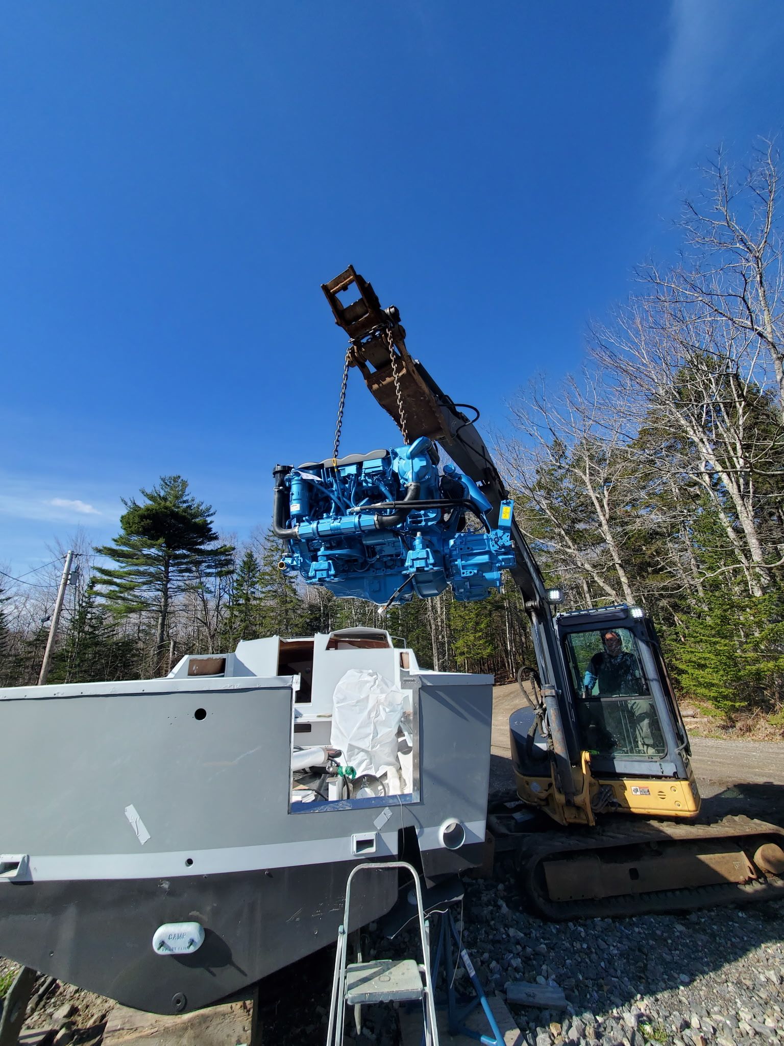 Excavator lifting engine into Black Watch Custom 35 boat, 1989.
