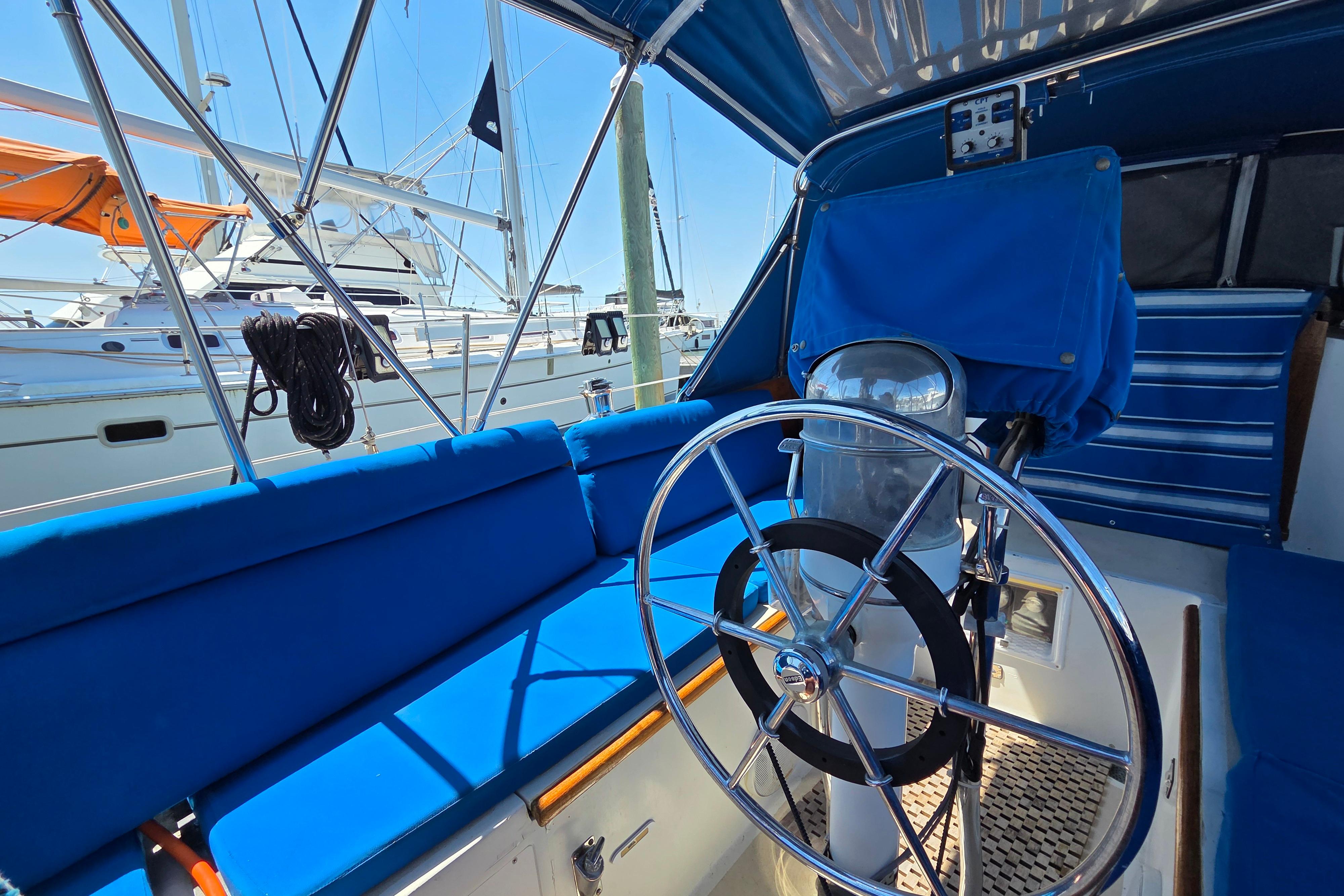 Interior view of a 1961 Hinckley Bermuda 40 sailboat with blue seating and steering wheel.