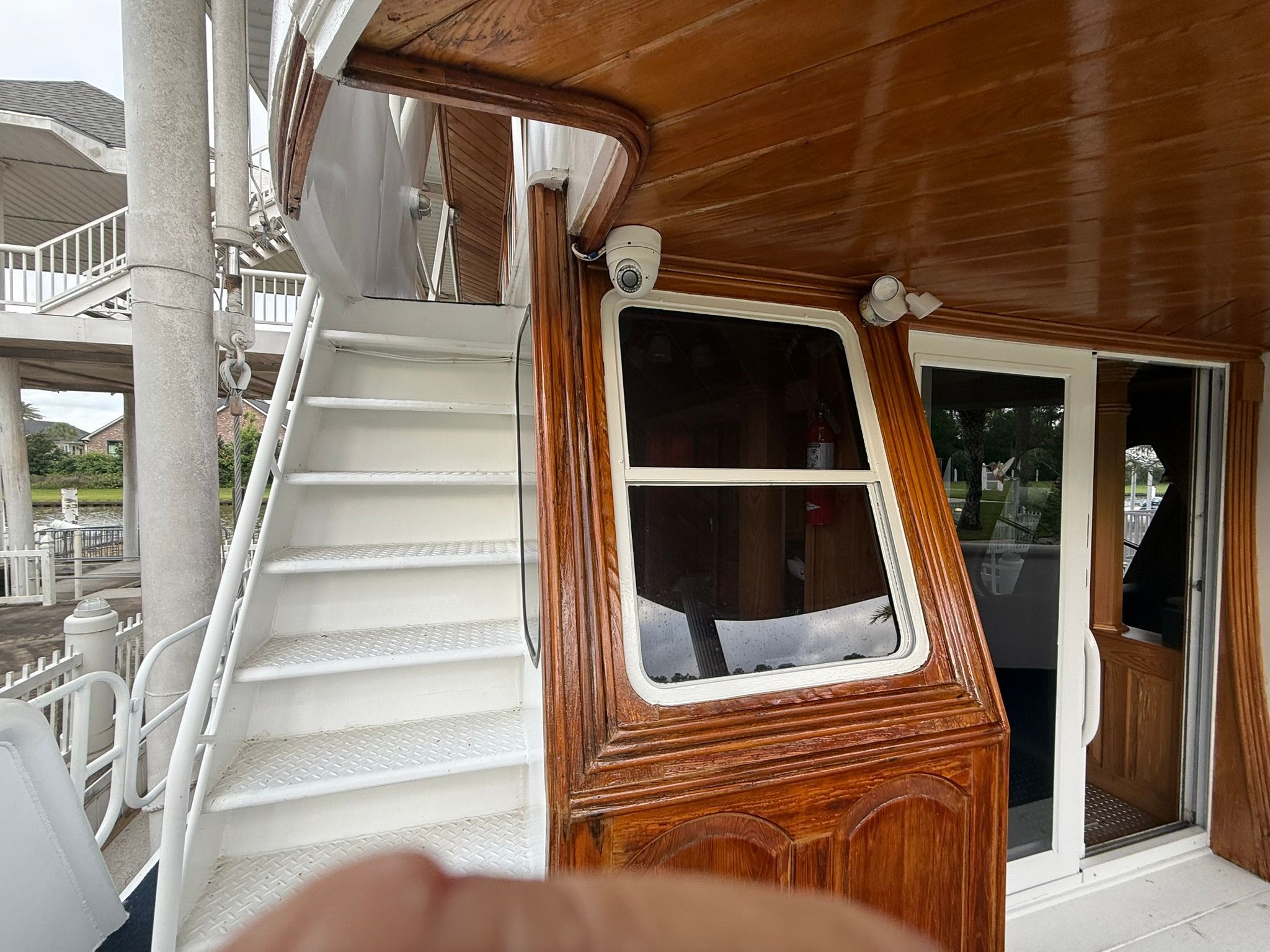 Wood-paneled boat with stairs and a window leading to an interior space.