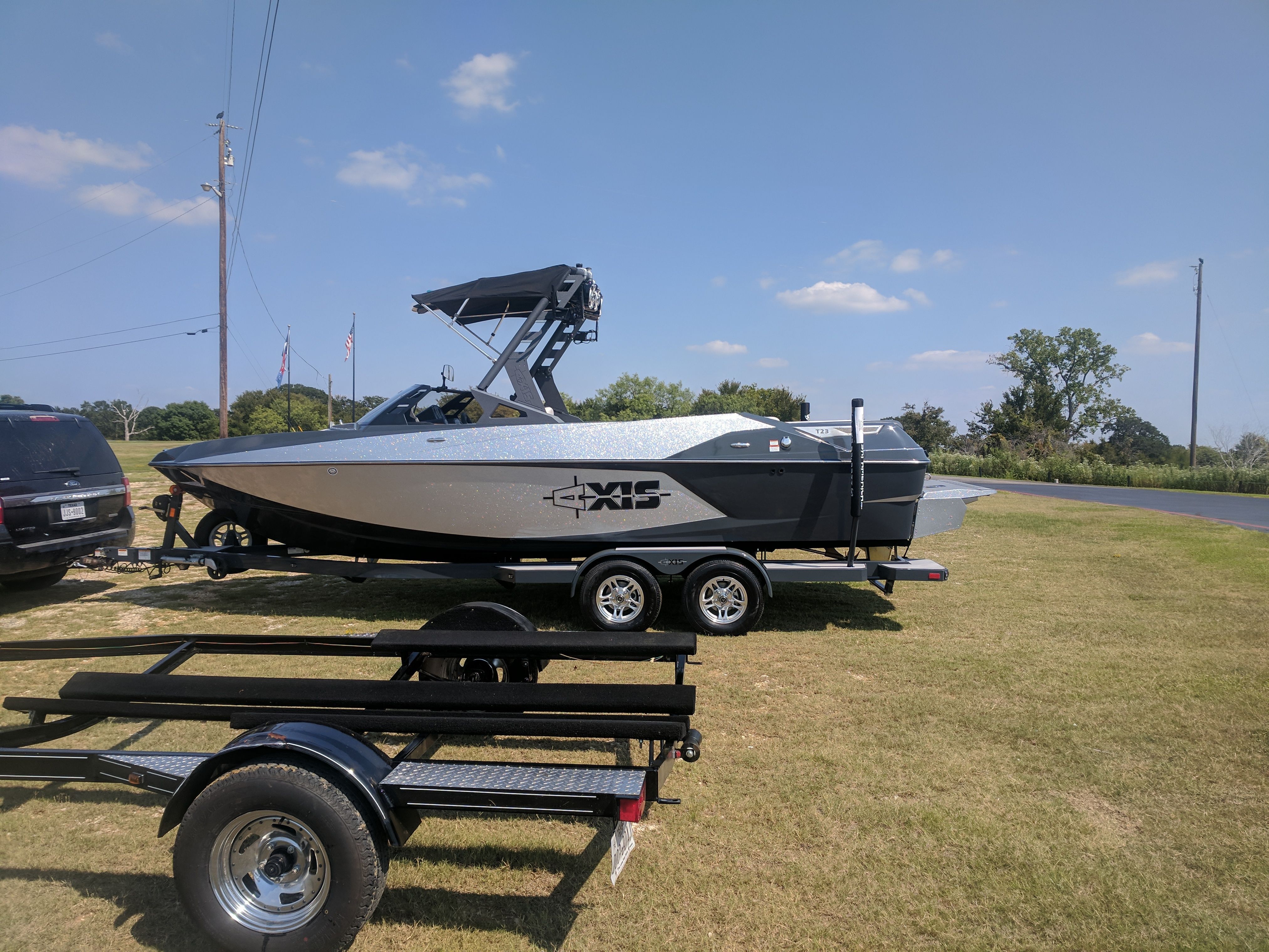 A 2017 Axis T23 boat is on a trailer on a grassy area.