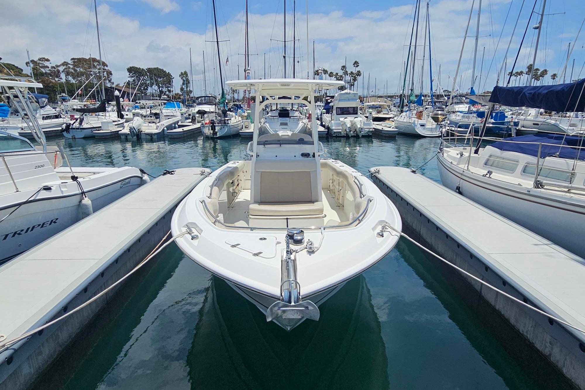 2017 Boston Whaler 230 Outrage docked at a marina, surrounded by sailboats.