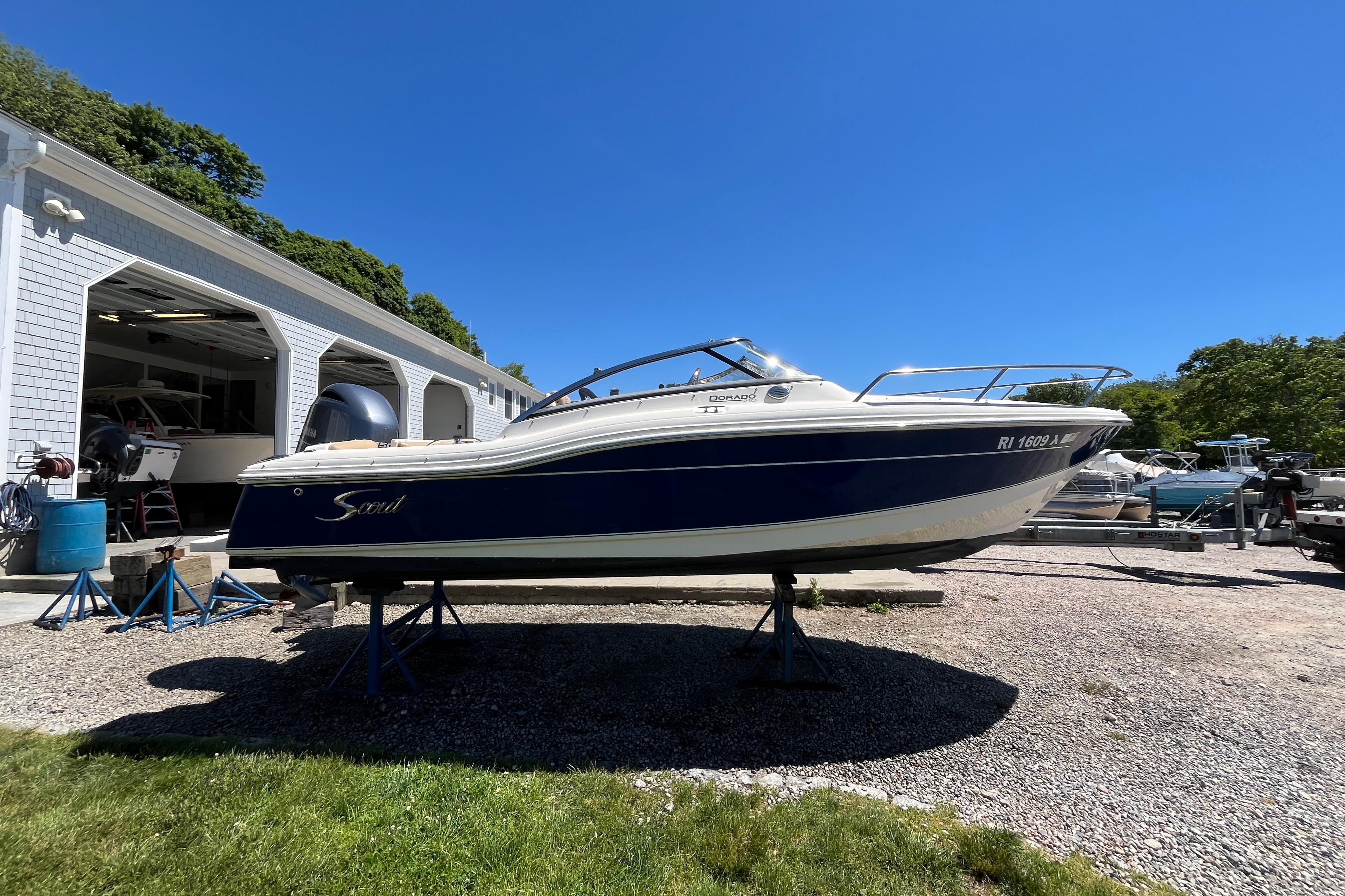 2017 Scout 210 Dorado boat on stands outside a garage under clear blue sky.