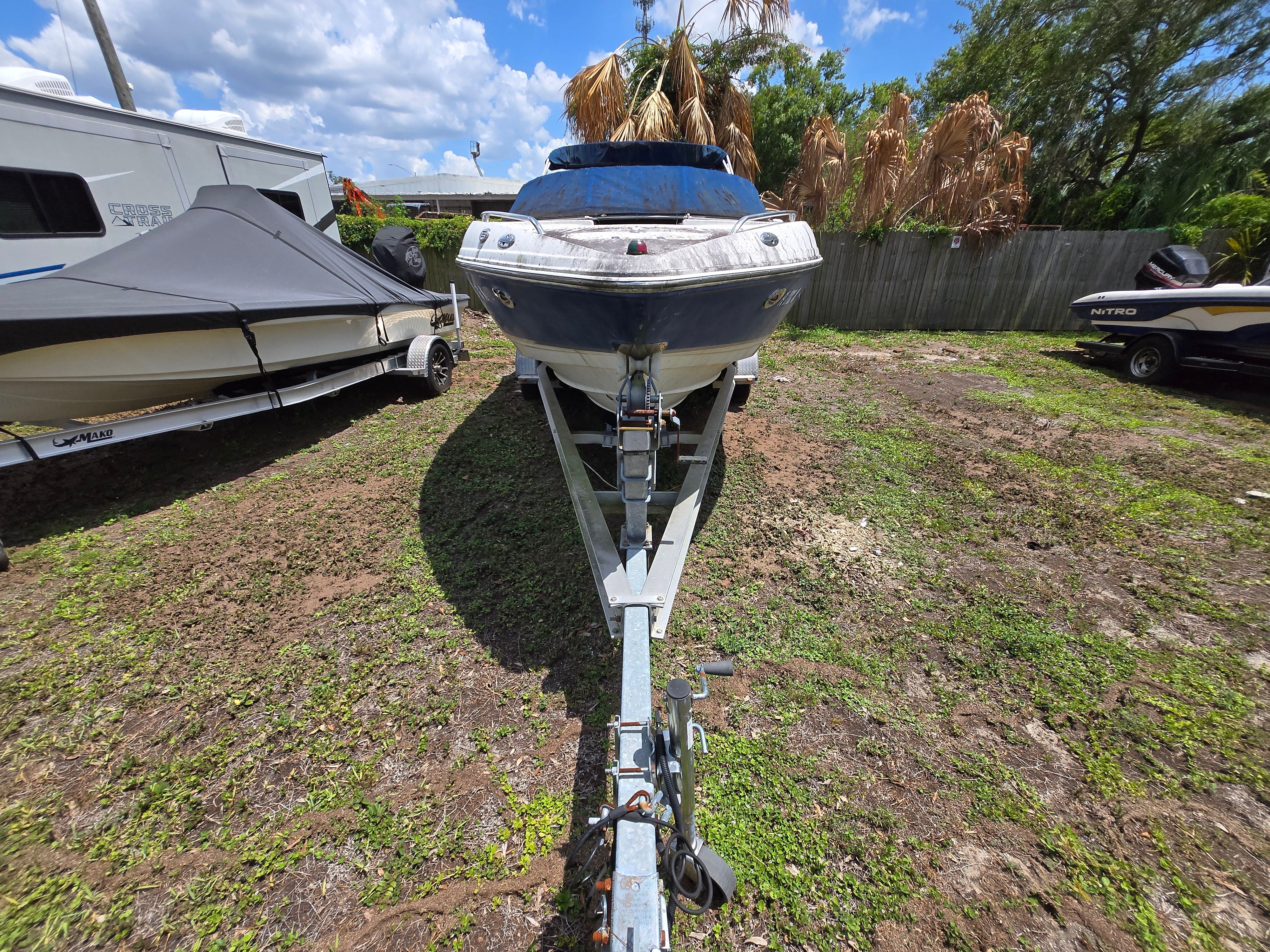 A 2006 Chaparral 220 SSi boat on a trailer in a grassy area.