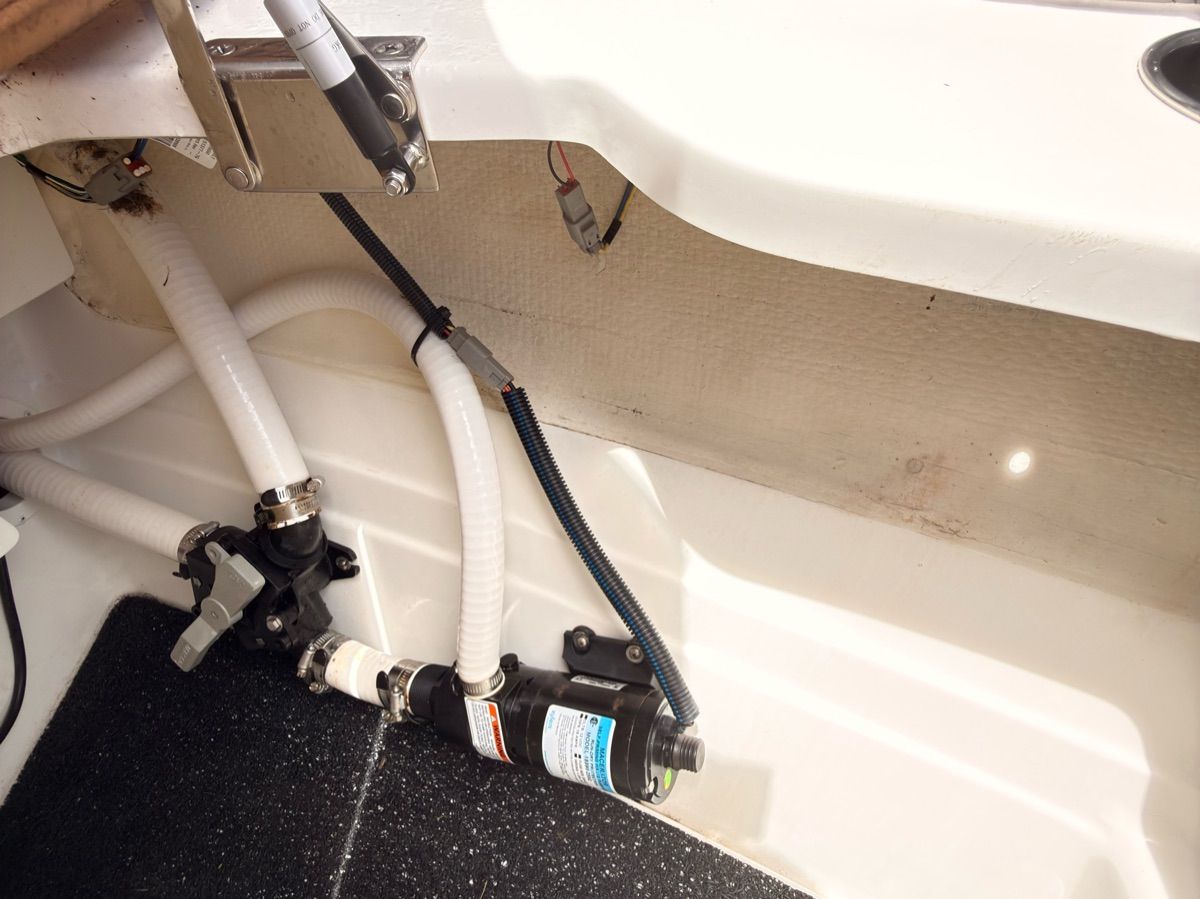 A view of the engine compartment of a 2024 Cobalt R8 Outboard with hoses and valves.