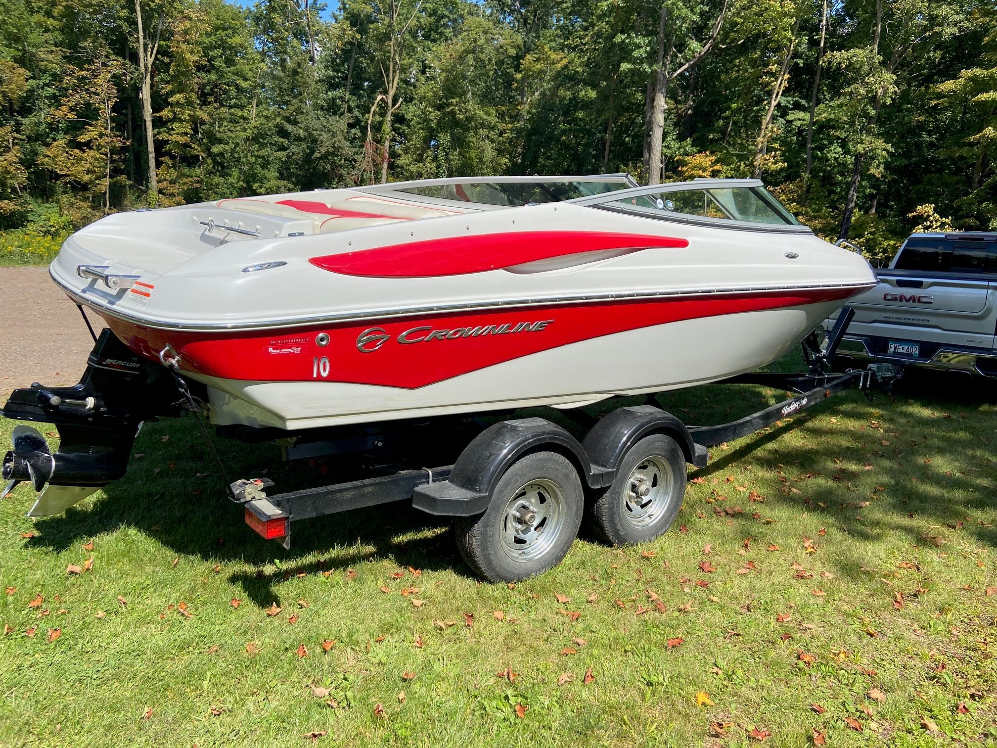 A 2011 Crownline 21 SS boat on a trailer, surrounded by trees.