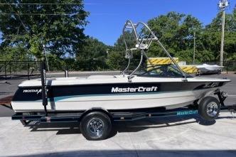 1996 MasterCraft ProStar 190 boat on trailer, parked outdoors, with trees in the background.