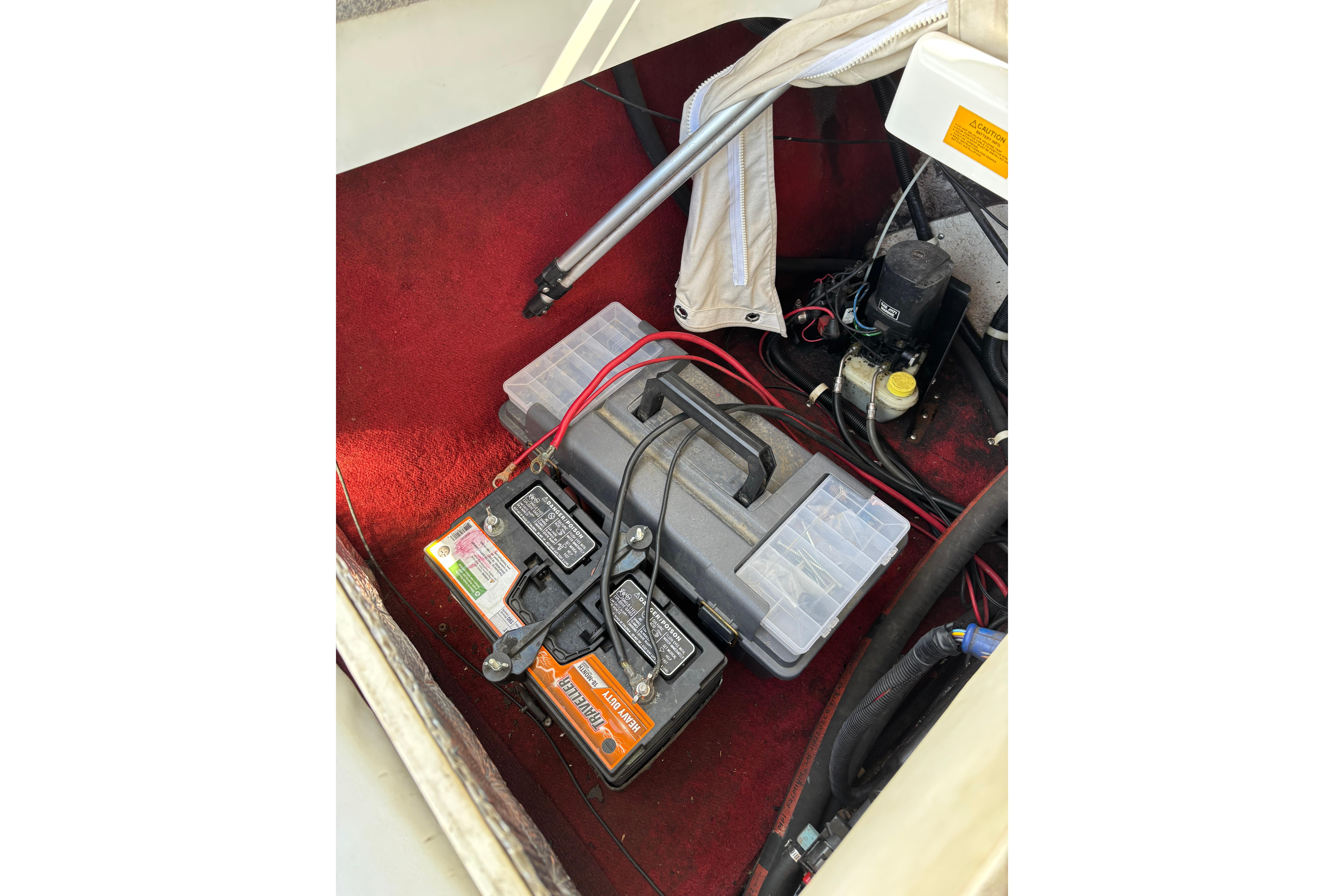 Battery compartment of a 1993 Larson SEi 200 Cuddy I/O boat with red carpeting.