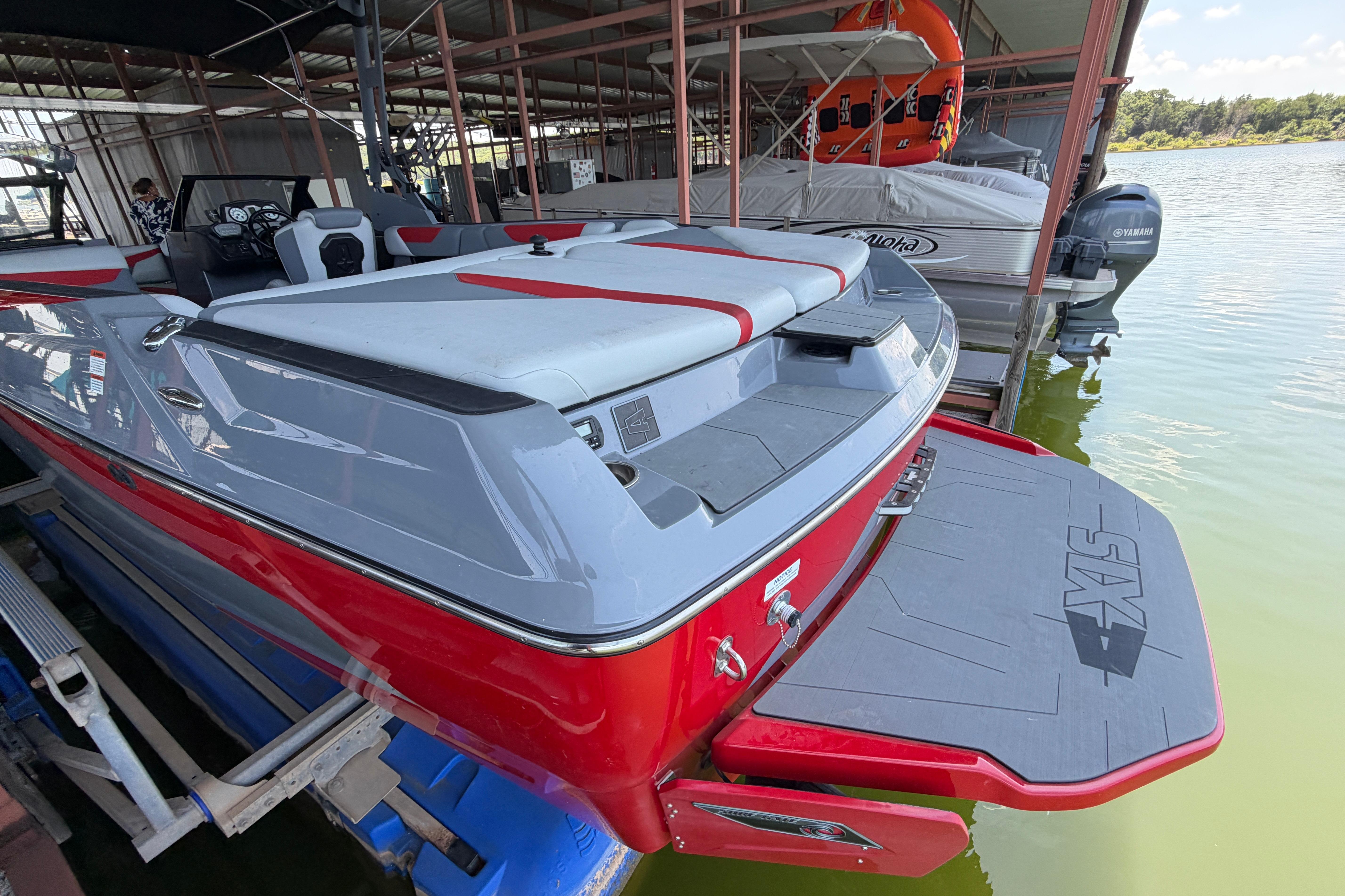 2021 Axis A24 boat docked, featuring sleek red and gray design with swim platform.