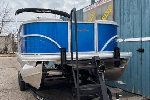 2026 Sun Tracker Party Barge 20 DLX pontoon boat with blue exterior, parked on trailer.