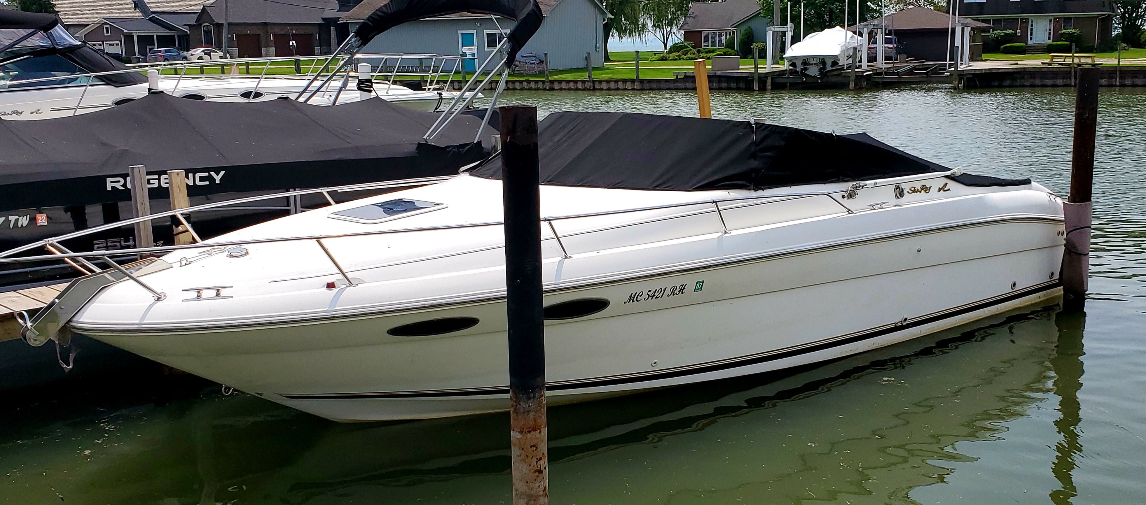 1996 Sea Ray 280 Sun Sport boat docked in a marina, covered with a black tarp.