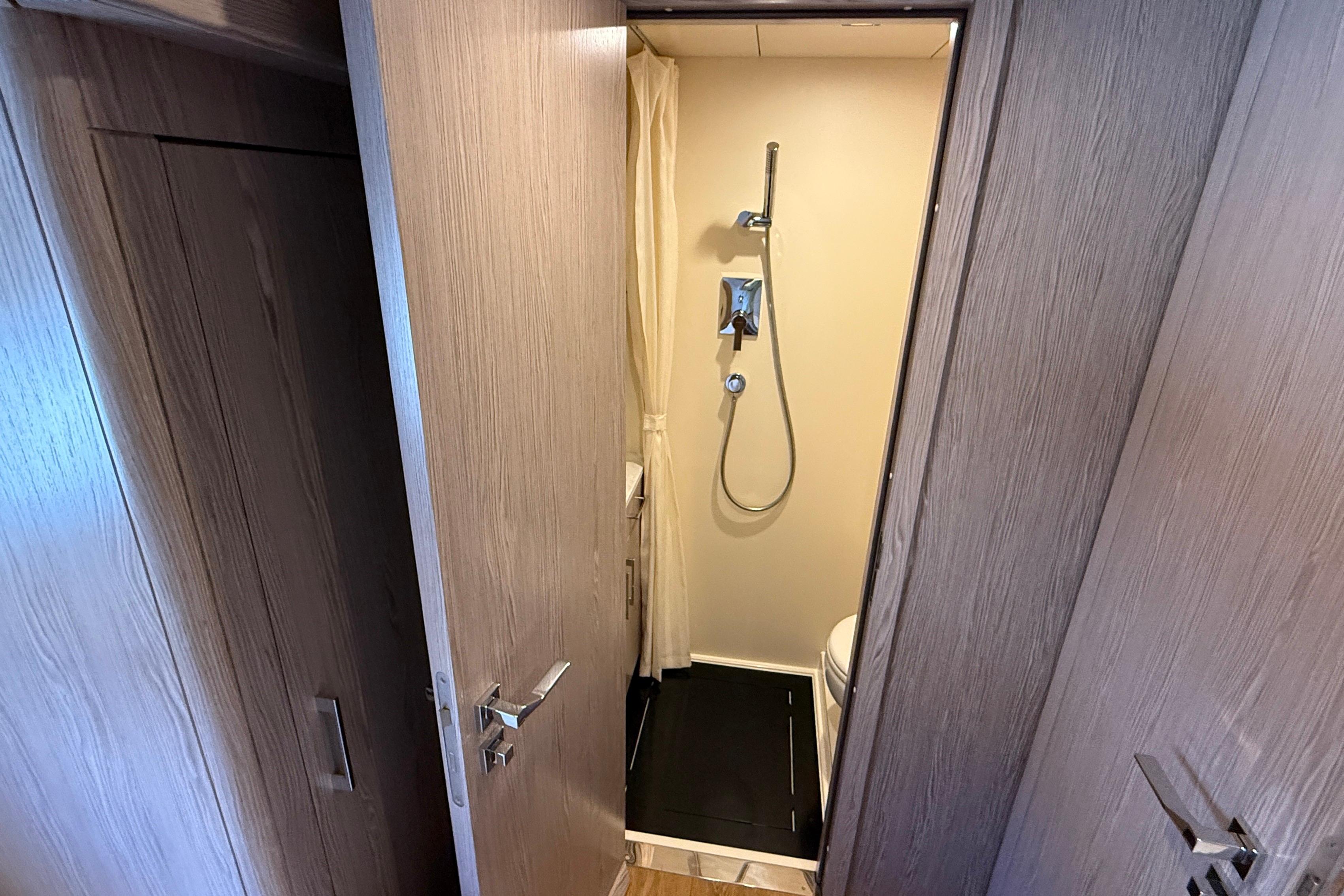 Compact bathroom with shower in 2022 Sirena 58 yacht, featuring wooden doors and modern fixtures.