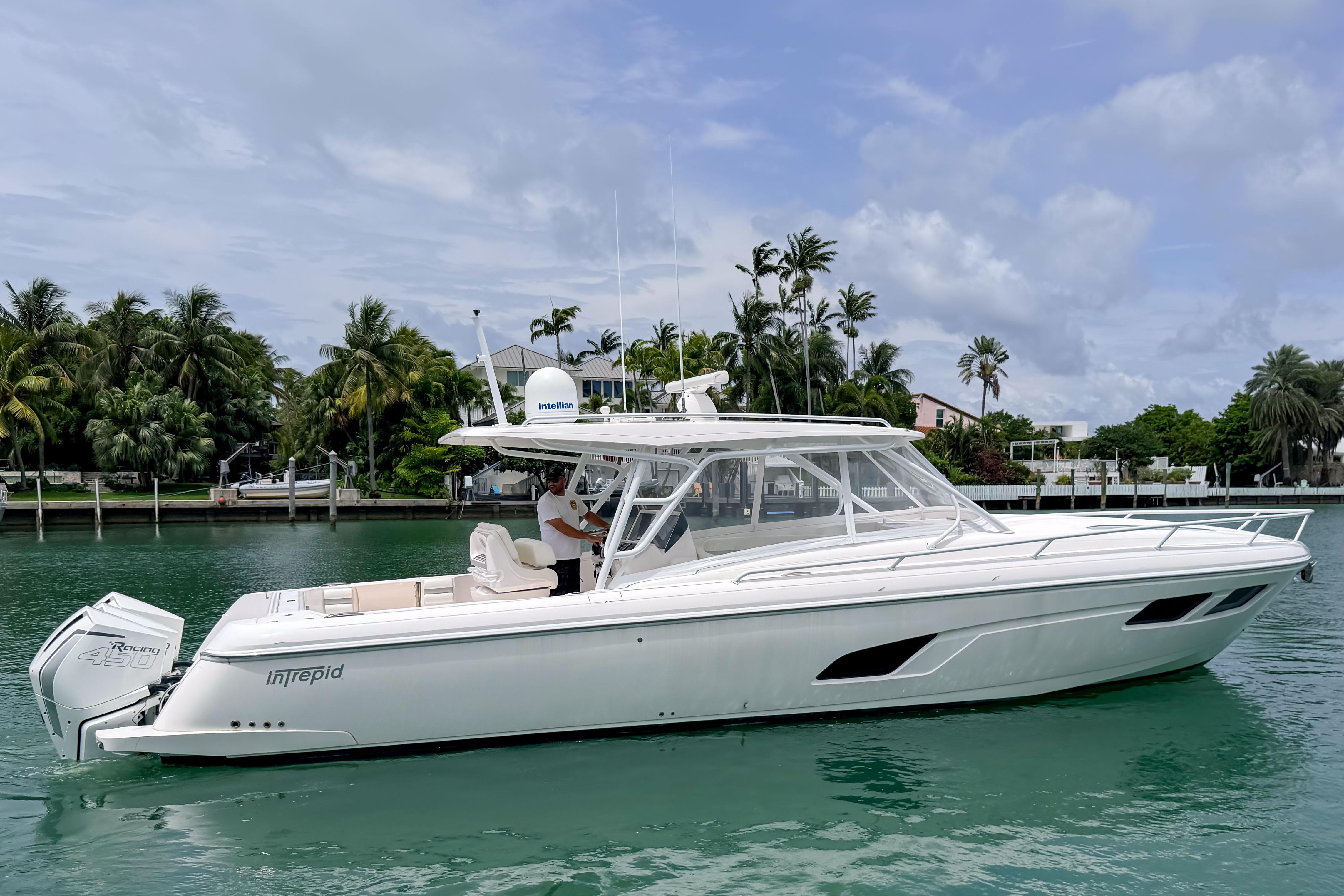 2021 Intrepid 409 Valor boat cruising on a tropical waterway with palm trees.