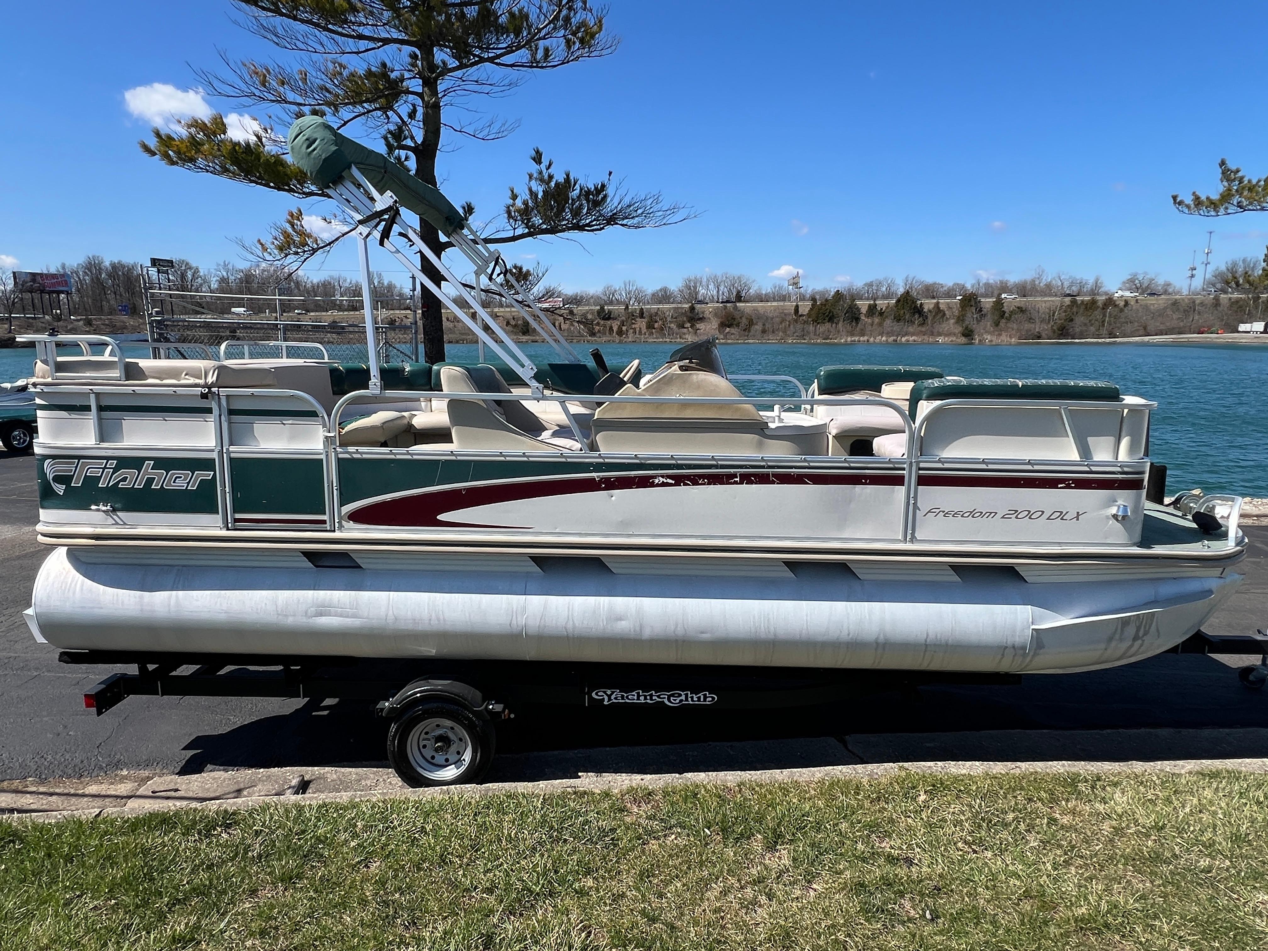 1998 Fisher Freedom 200 DLX pontoon boat on trailer by a lake.
