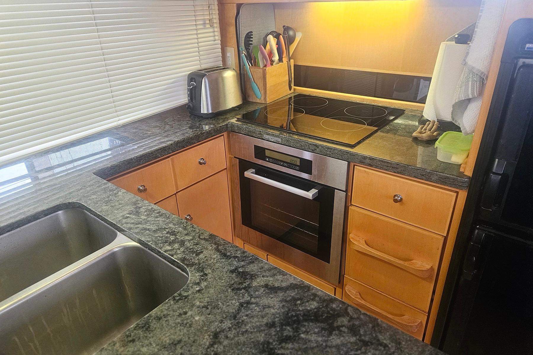 Modern kitchen with granite countertops, stainless steel appliances, and wooden cabinetry in a Symbol 55 model.