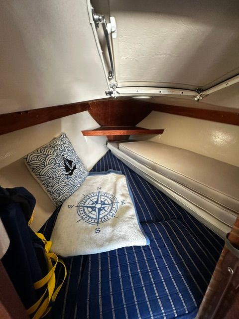Interior of a 1985 Catalina 27 with a blue mattress and nautical decorations.