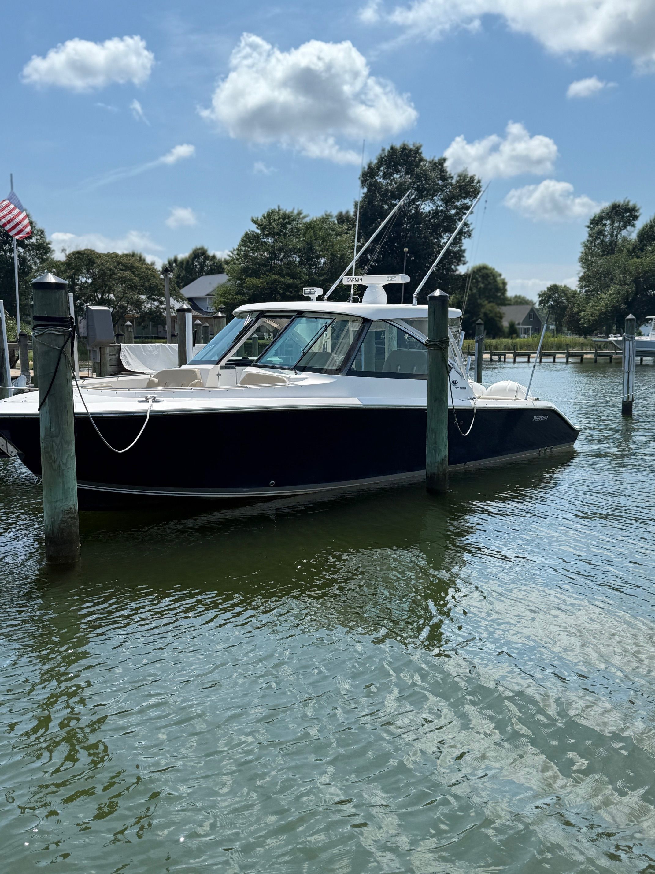 A 2016 Pursuit DC 325 Dual Console boat docked in calm waters, surrounded by trees.
