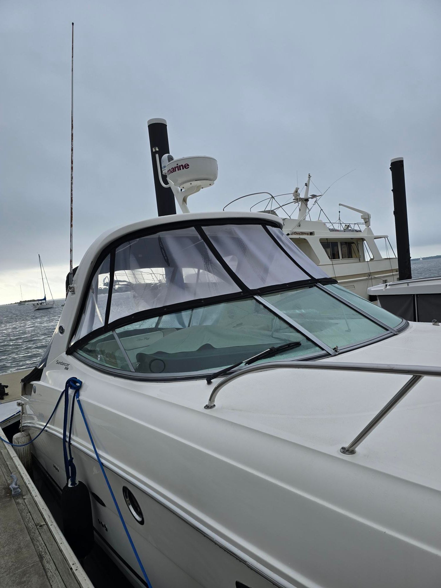 A Sea Ray Sundancer 310 boat docked, with a gray sky in the background.