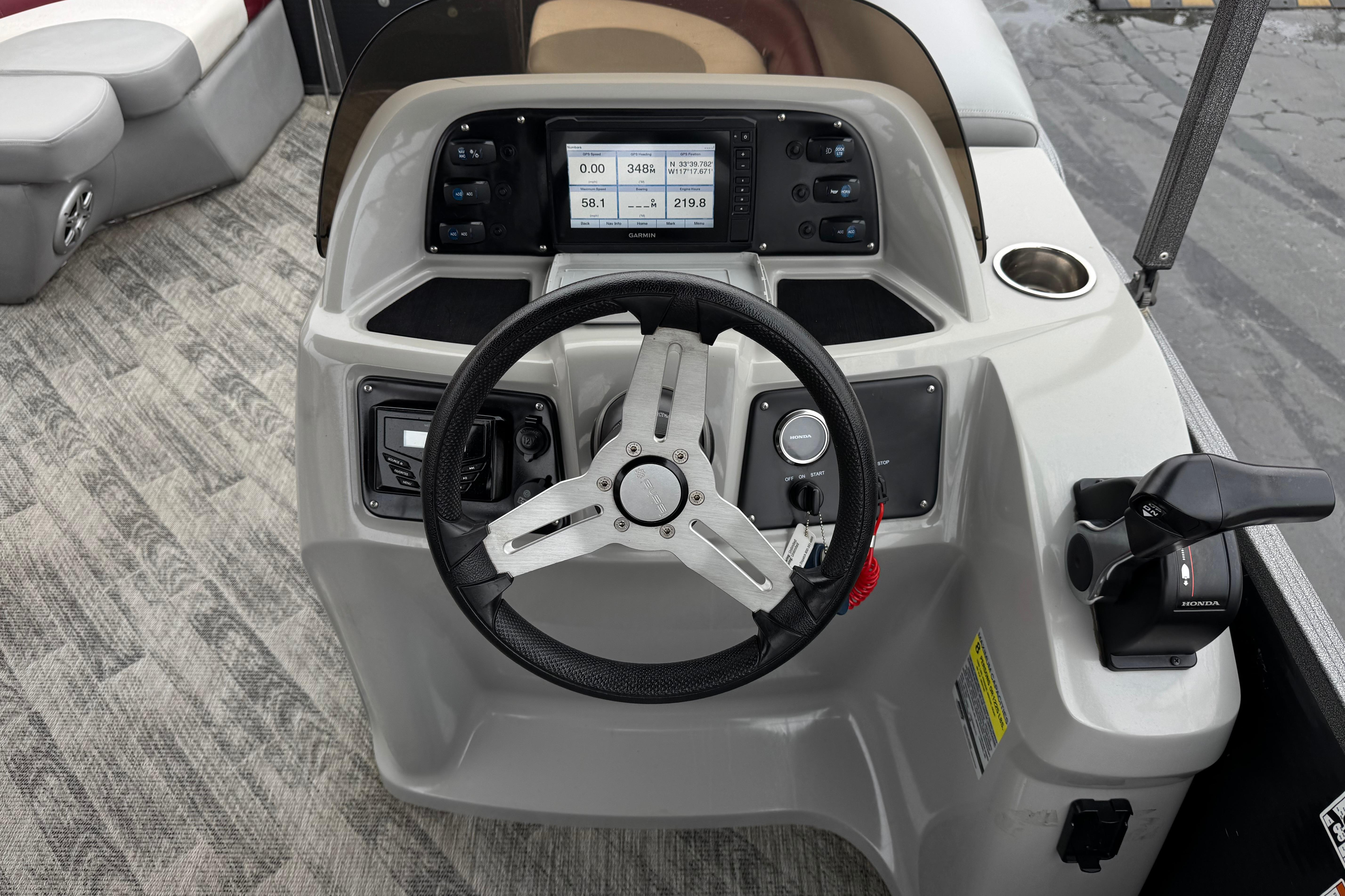 2020 Manitou 18 Aurora LE boat dashboard with steering wheel and control panel.