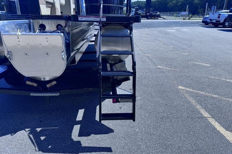 Rear view of 2027 Manitou Aurora 23 RF SHP boat with ladder on asphalt.