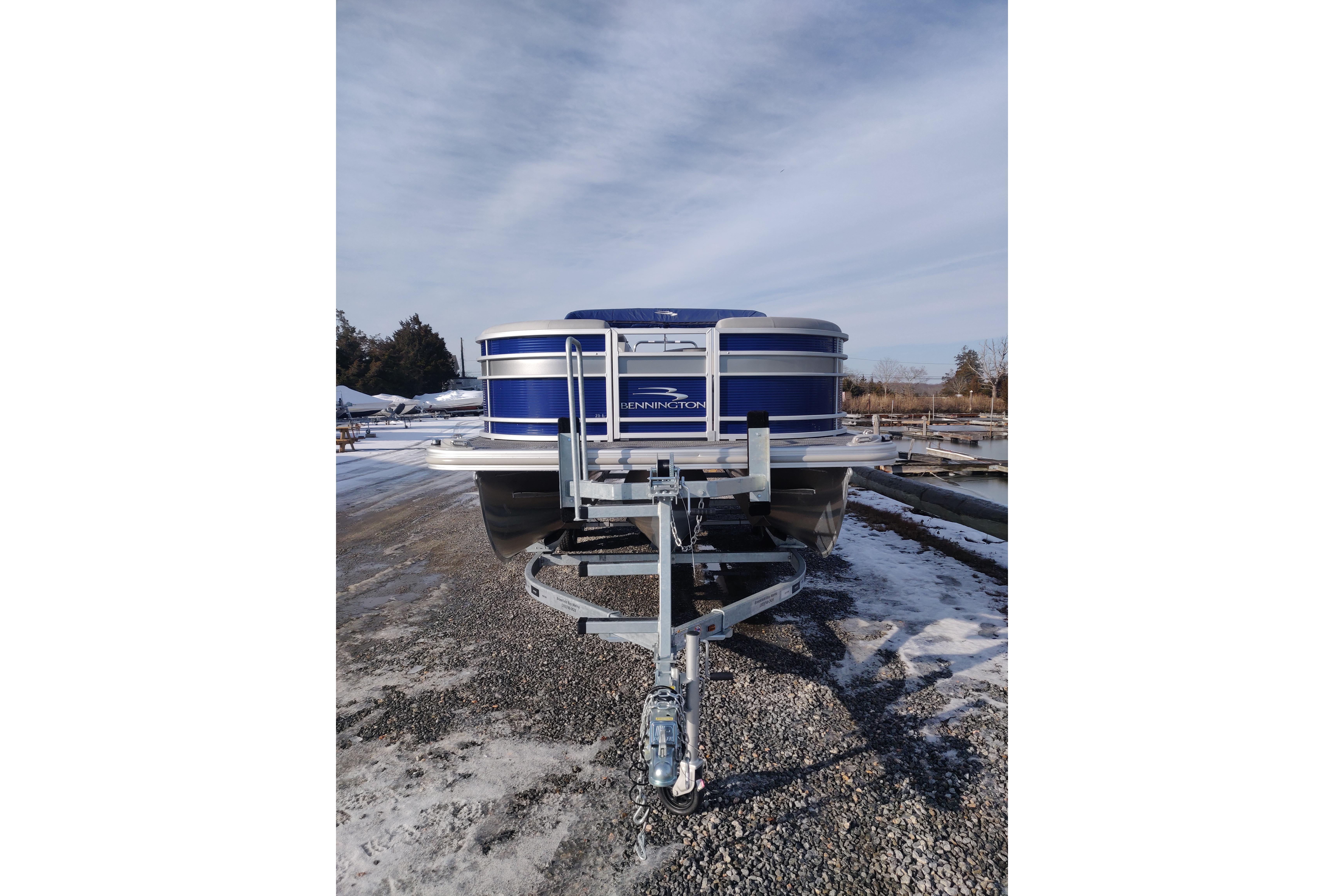 2023 Bennington 21LSB pontoon boat on trailer, parked on gravel.
