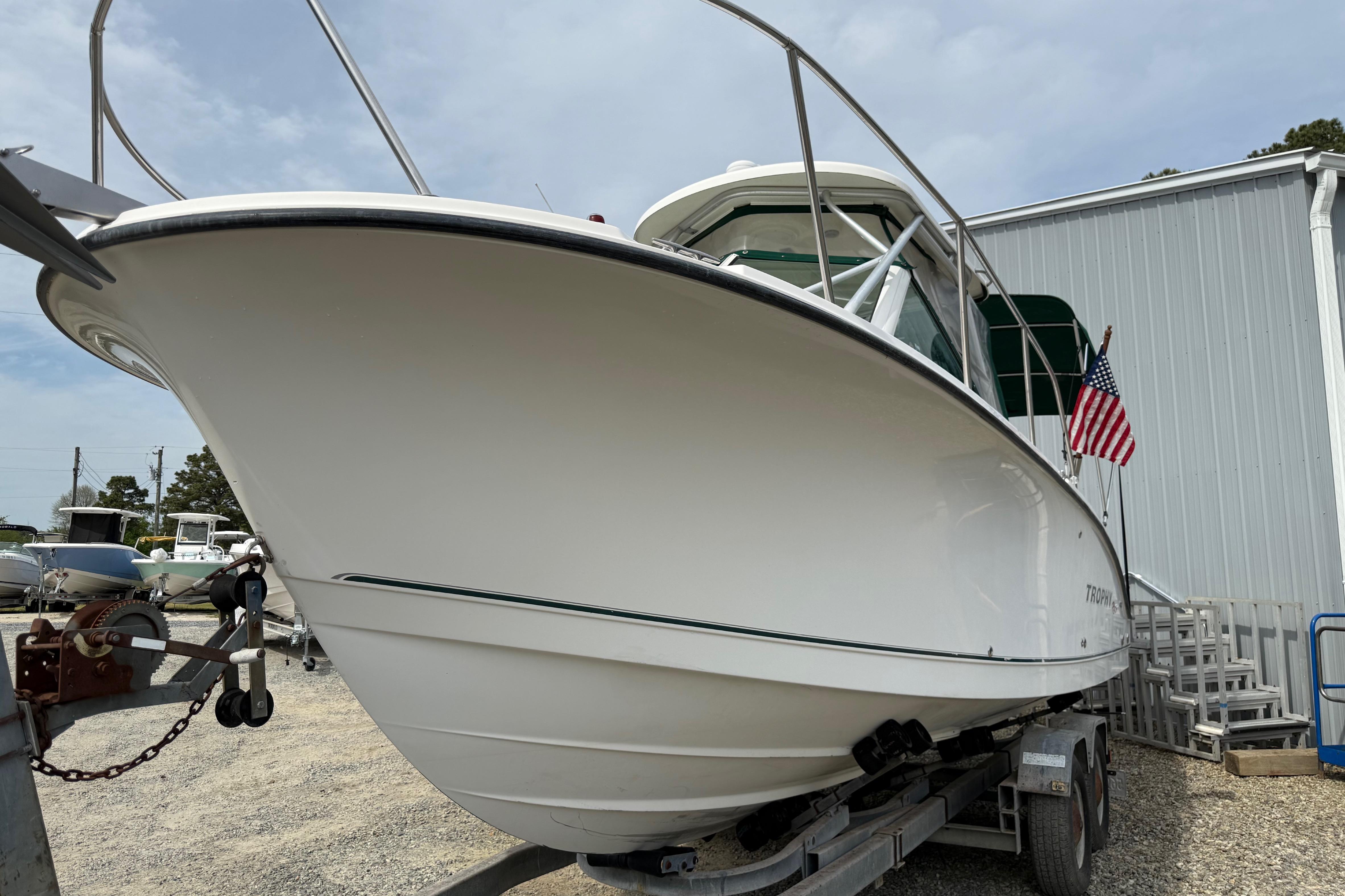 2006 Trophy 2502 Walkaround boat on trailer, American flag displayed, parked outdoors.