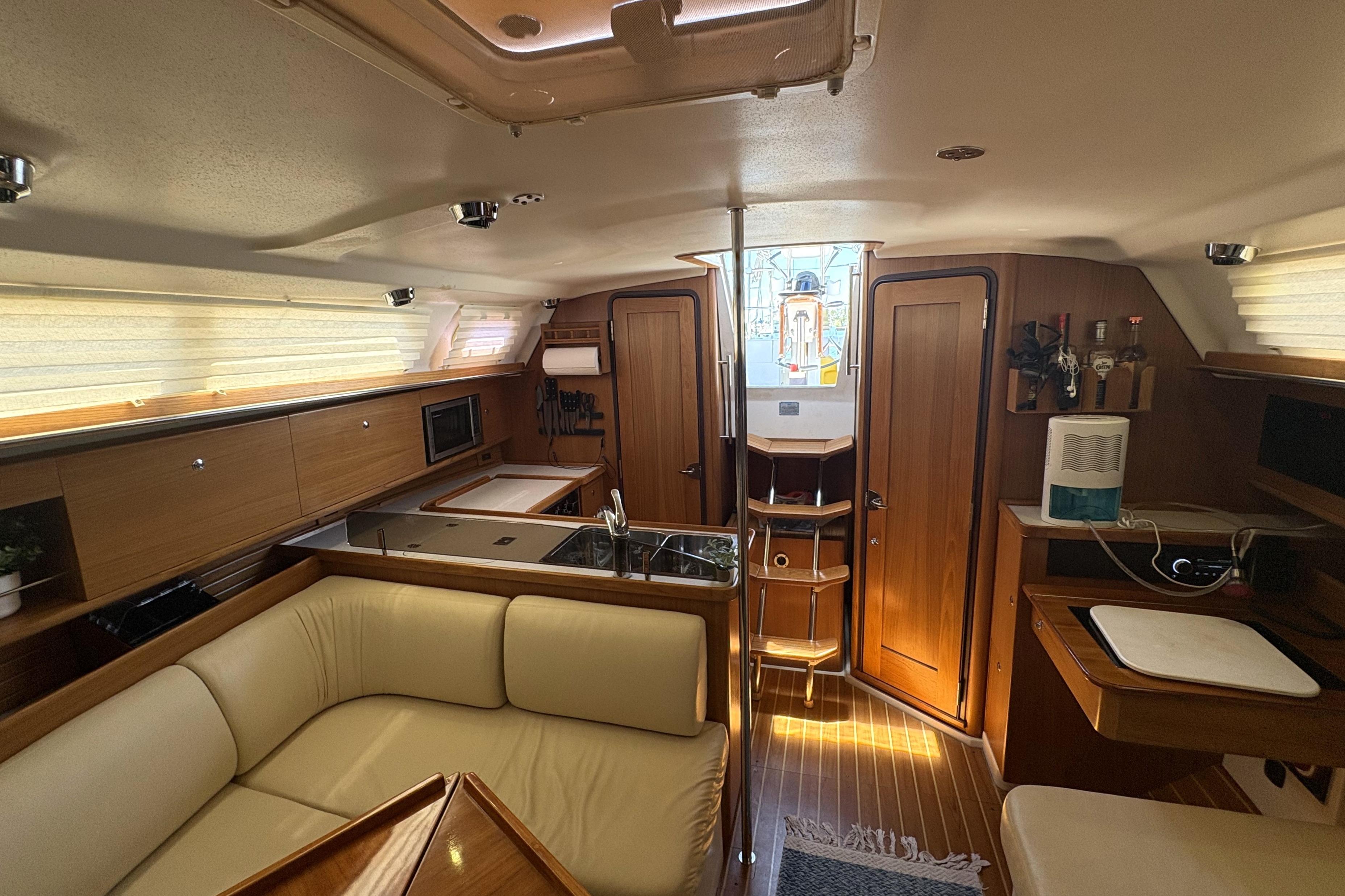 Interior of a 2011 Catalina 355 sailboat with cozy seating and wooden cabinetry.