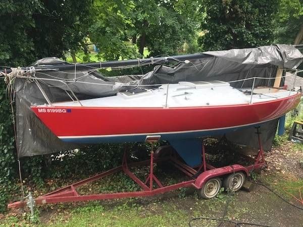 Red 1978 J Boats J/24 sailboat on trailer outdoors.