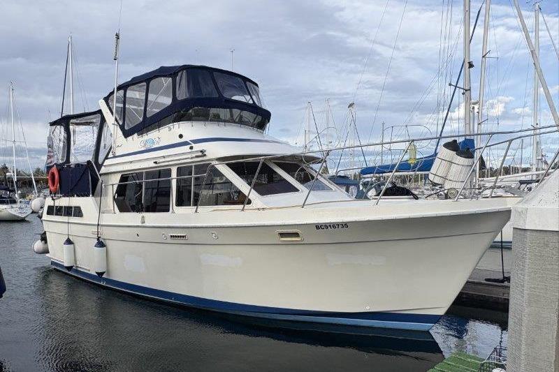 1987 Tollycraft 34 Sundeck Motor Yacht docked in a marina, featuring a blue canopy.