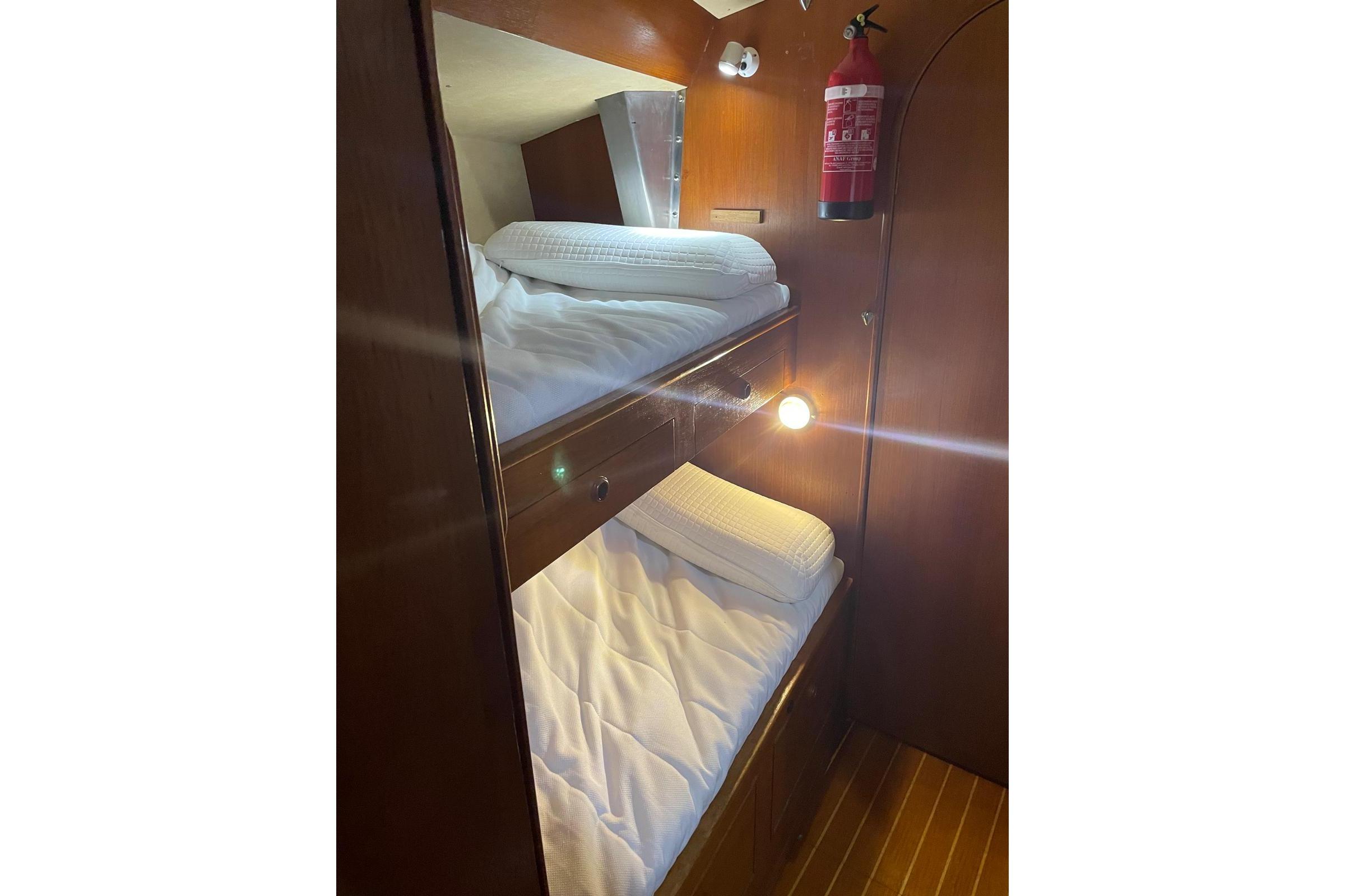 Interior of 1985 Oyster 435 yacht with wooden bunk beds and fire extinguisher.