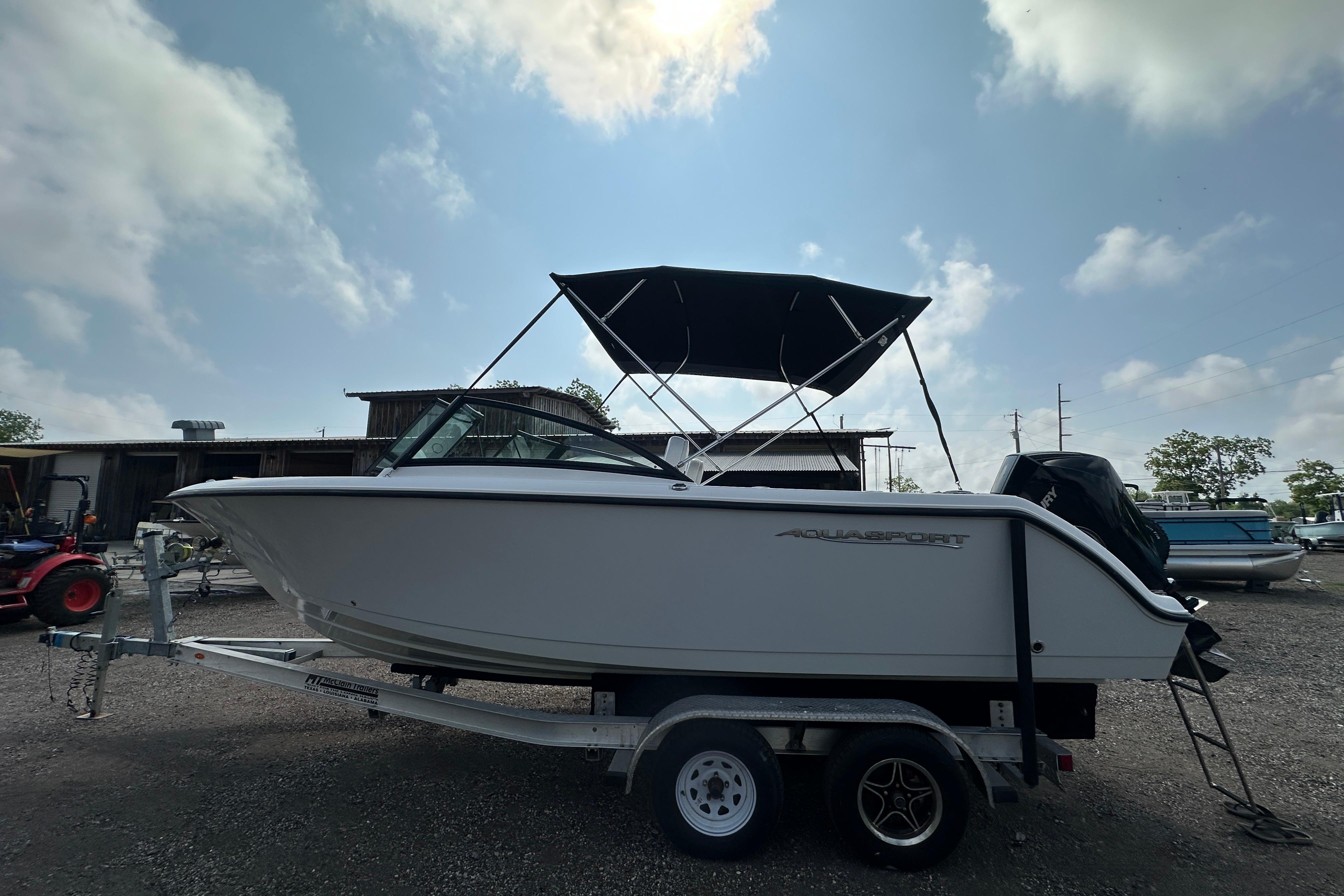 2024 Aquasport 2200 Dual Console boat on trailer under a cloudy sky.