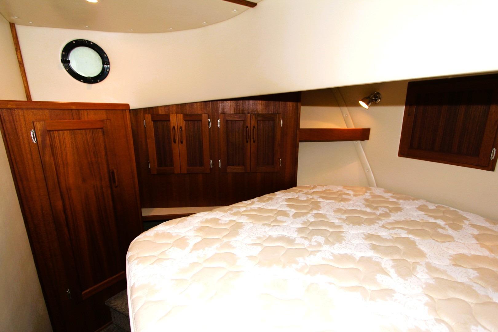 Cozy cabin interior of 2002 Nordic Tug 37 with wooden cabinets and porthole.