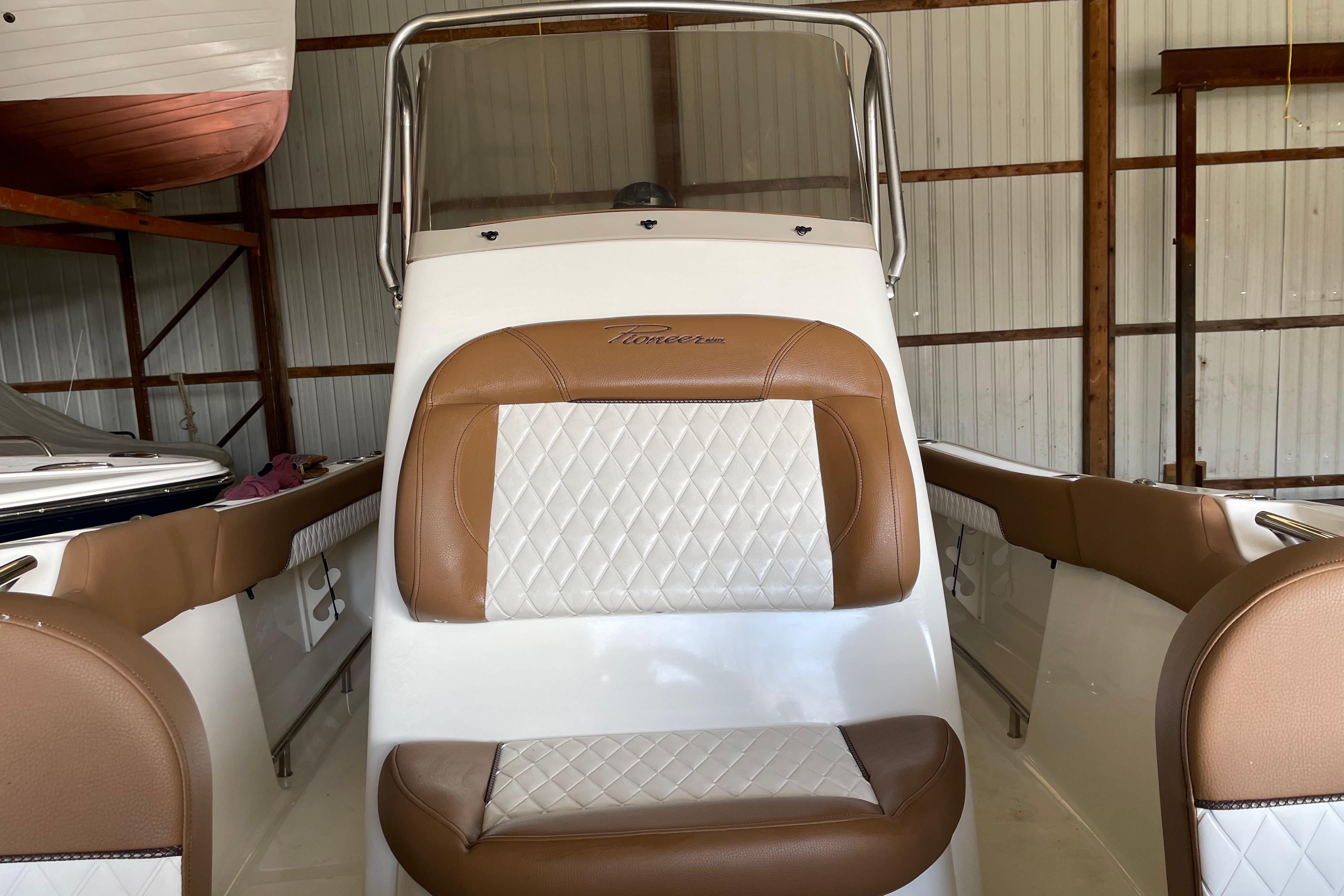 2026 Pioneer 202 Islander boat interior with brown and white seating in a storage facility.