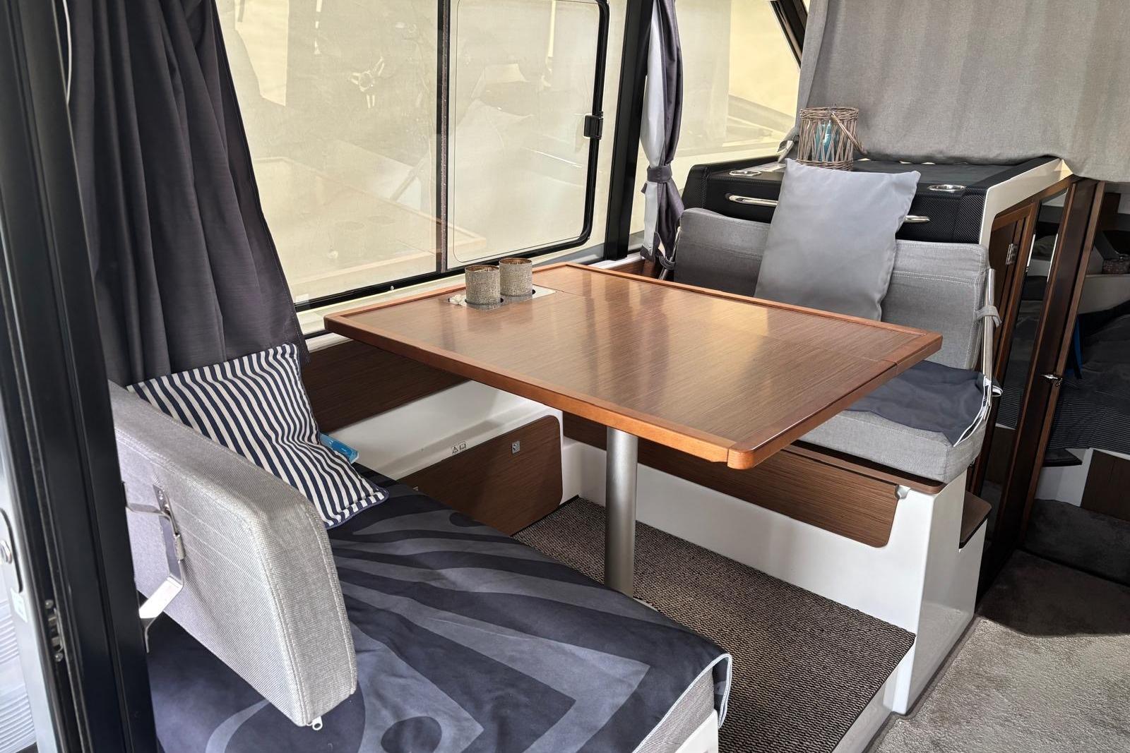 Interior of 2020 Jeanneau Merry Fisher 1095 with cozy seating and wooden table.
