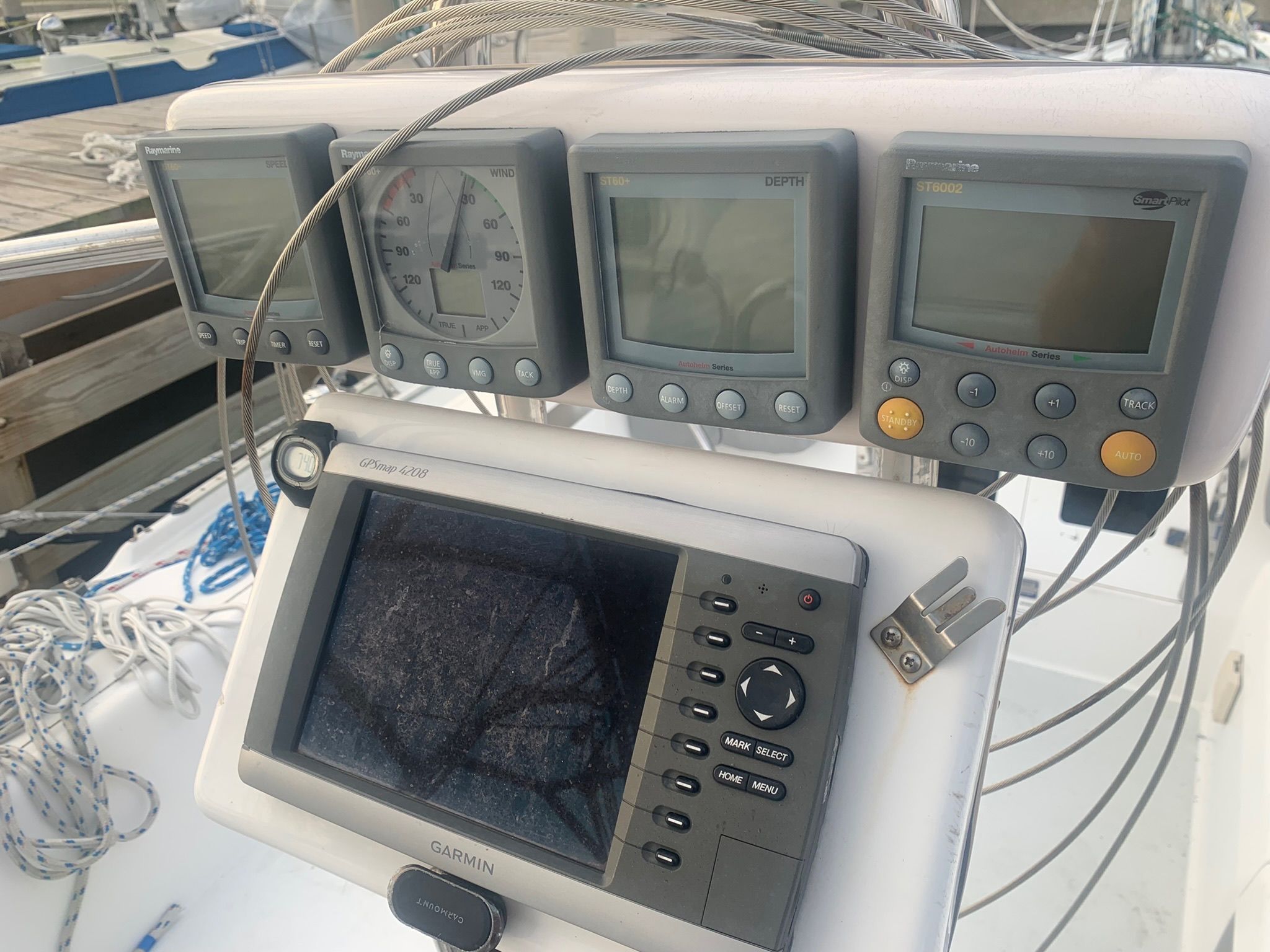A sailboat cockpit with multiple navigation instruments and a Garmin screen.