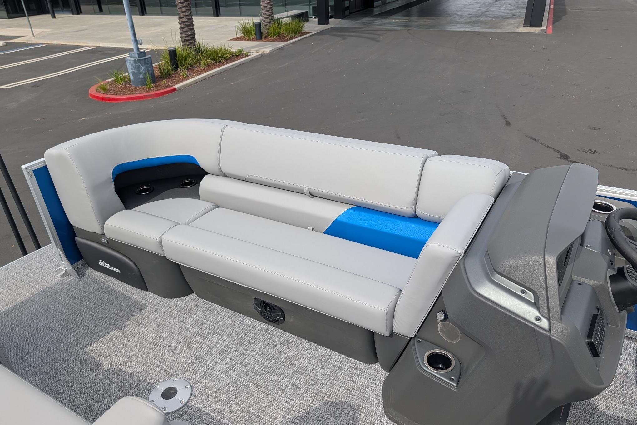 2026 Sun Tracker Party Barge 22 DLX with gray and blue seating, docked outdoors.