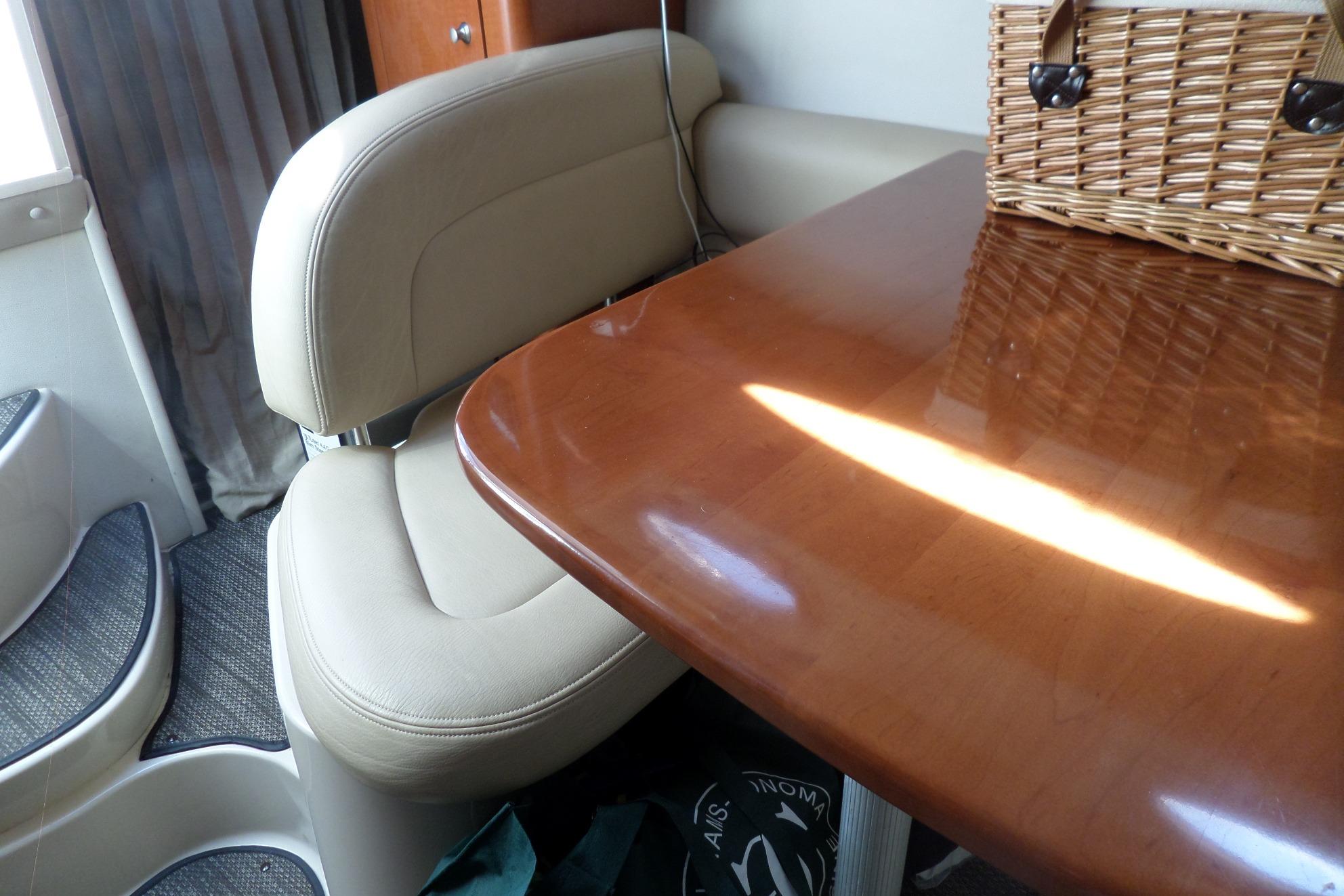 Interior of 2005 Chaparral Signature 270 with wooden table and beige seating.