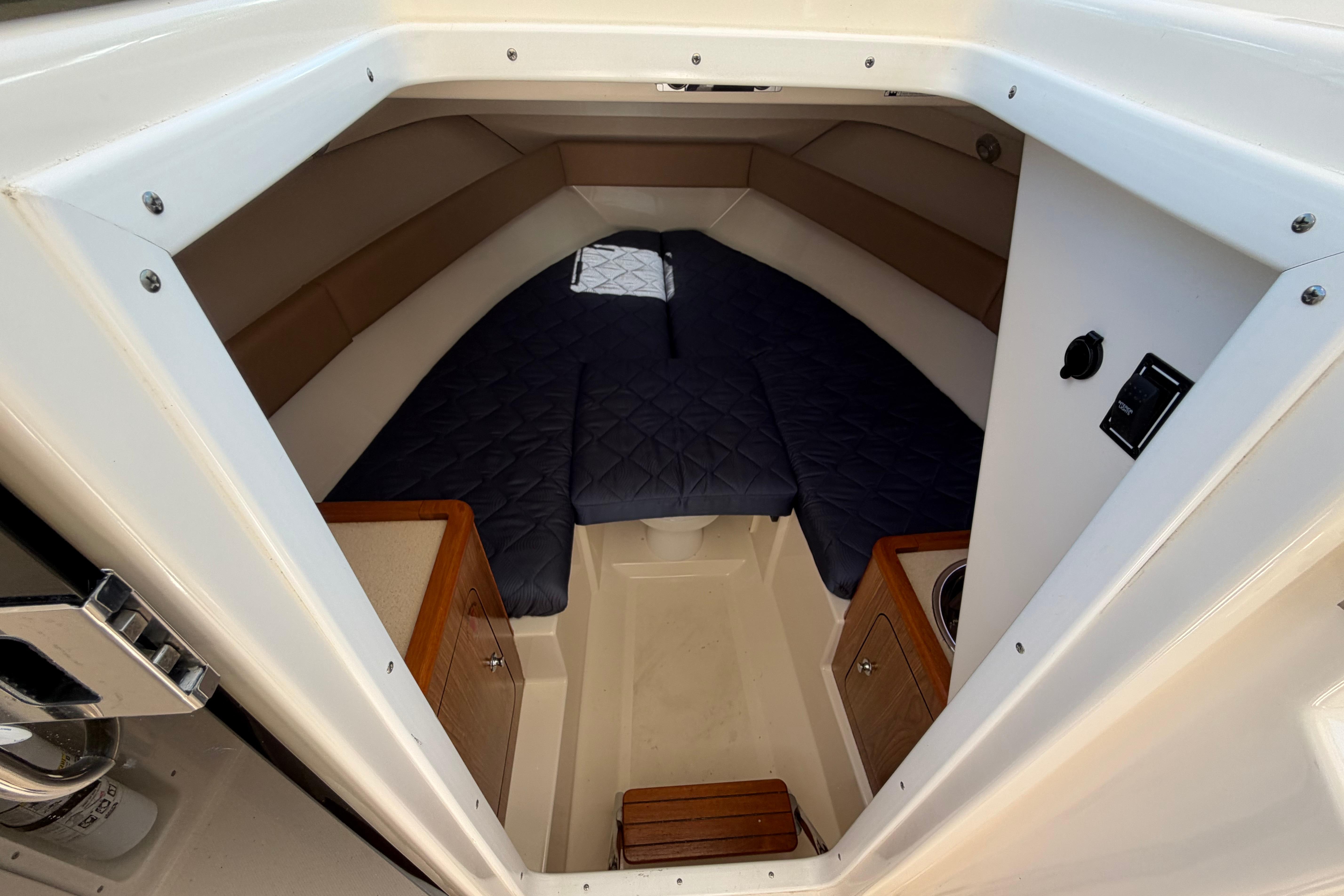 2010 Pursuit OS 255 Offshore cabin interior with bed, storage, and compact design.