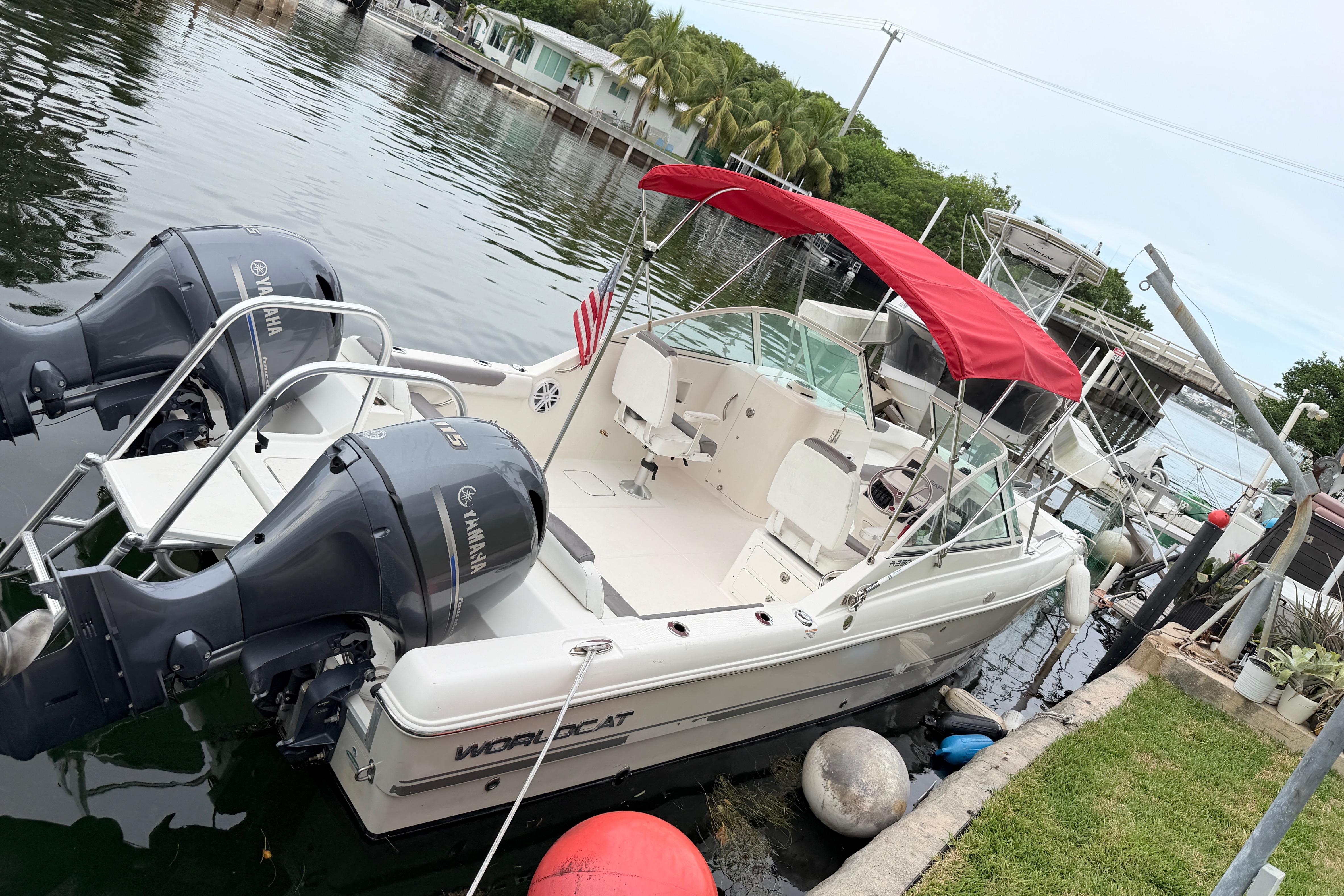 2019 World Cat 230 DC boat docked with dual Yamaha engines and red canopy.