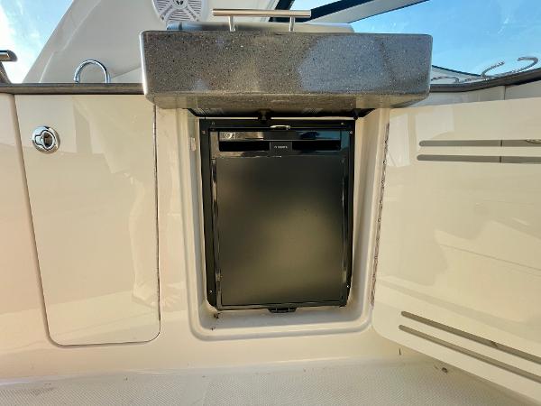 2014 Sea Ray 330 Sundancer boat kitchenette with compact fridge and sink.