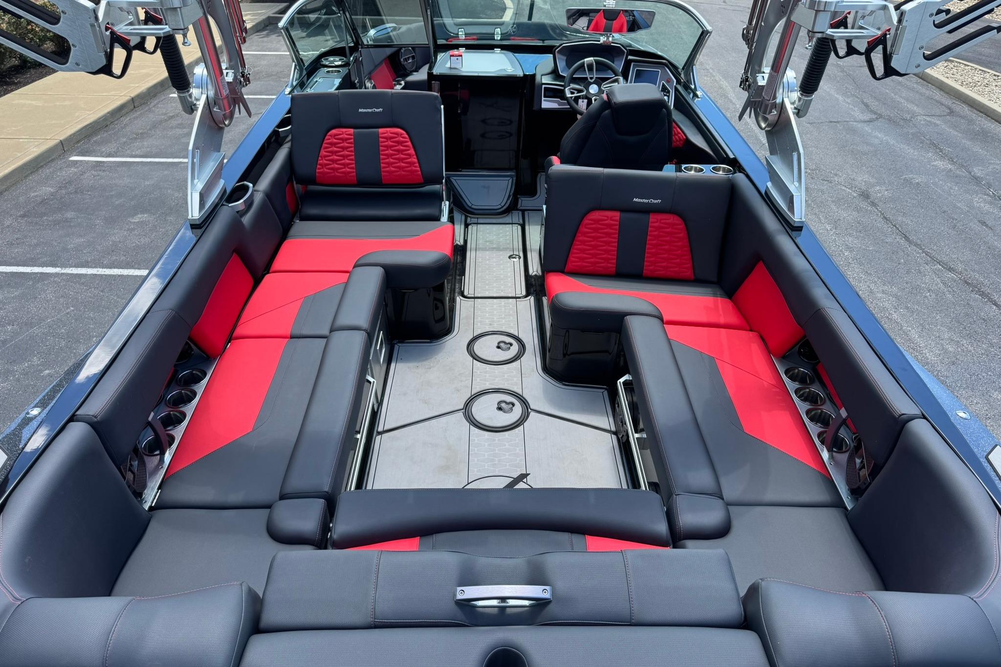 2021 MasterCraft X26 boat interior with red and black seating, cup holders, and sleek design.