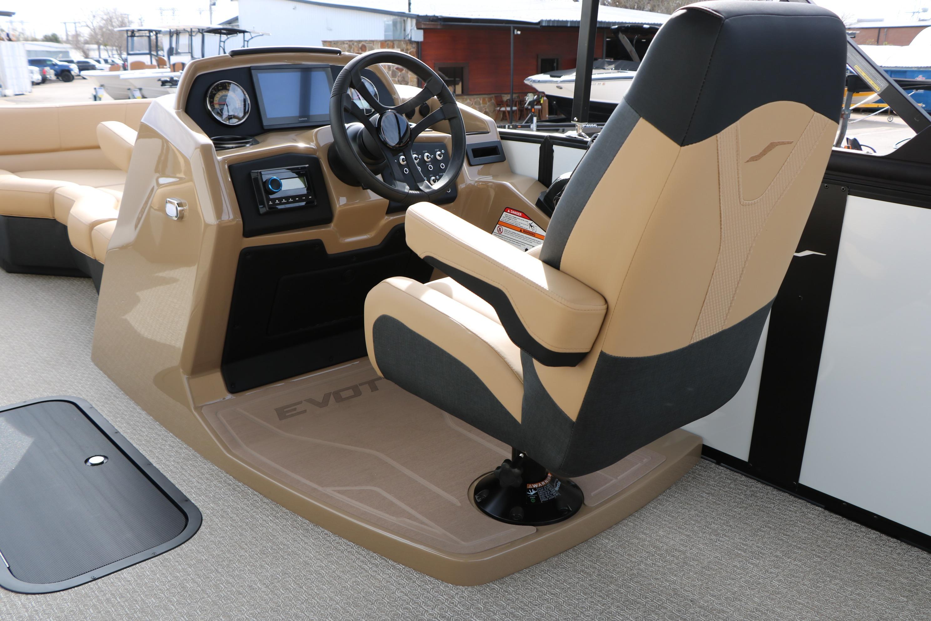 Captain's seat and dashboard of 2026 Evotti 523CS boat, featuring modern controls and beige upholstery.