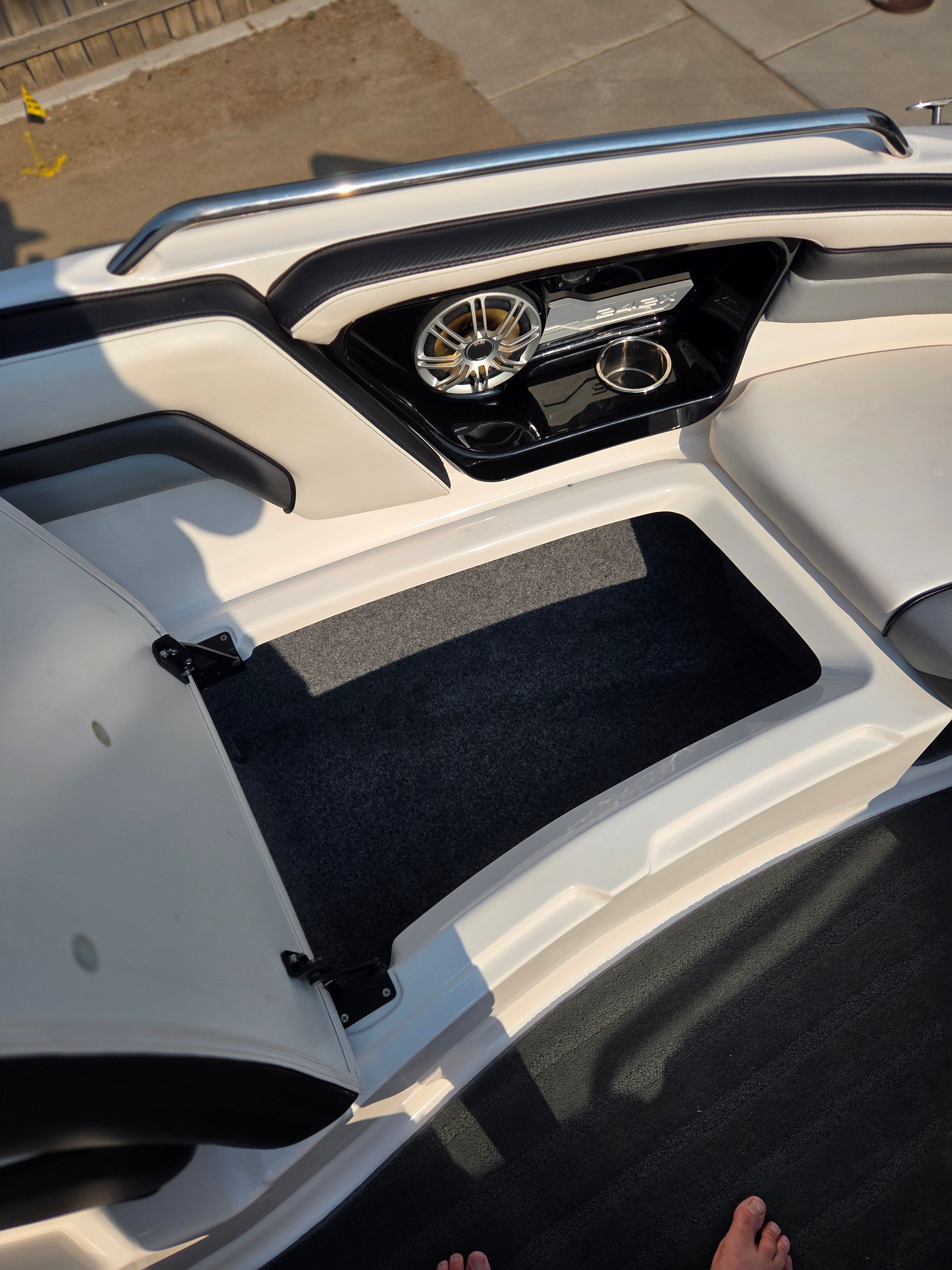 Interior view of a boat with white seating and speakers.