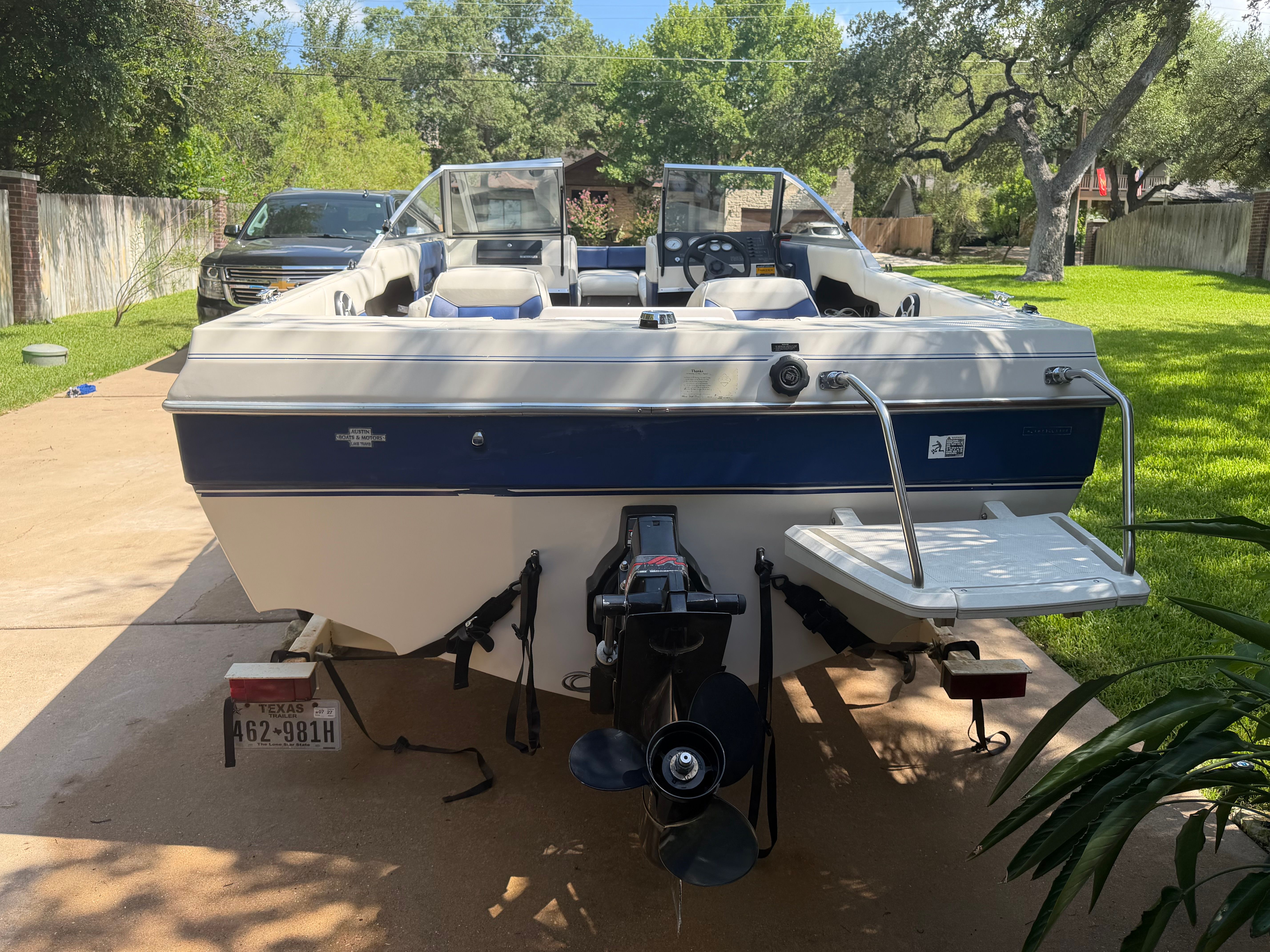 A 1994 Bayliner CAPRI on a driveway. It features a blue and white design with an outboard motor.