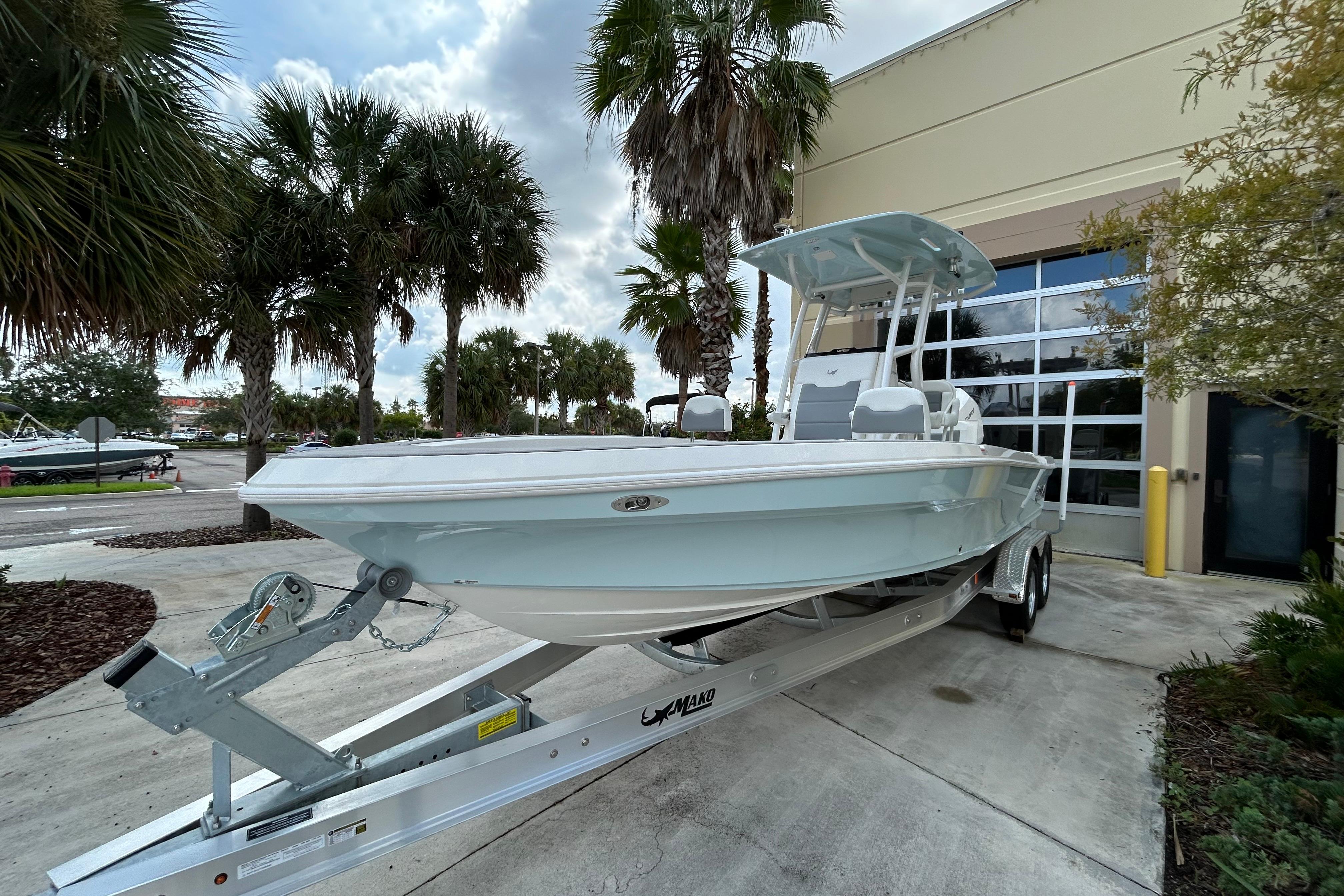 2025 Mako 24 APEX boat on trailer, parked outdoors near palm trees.
