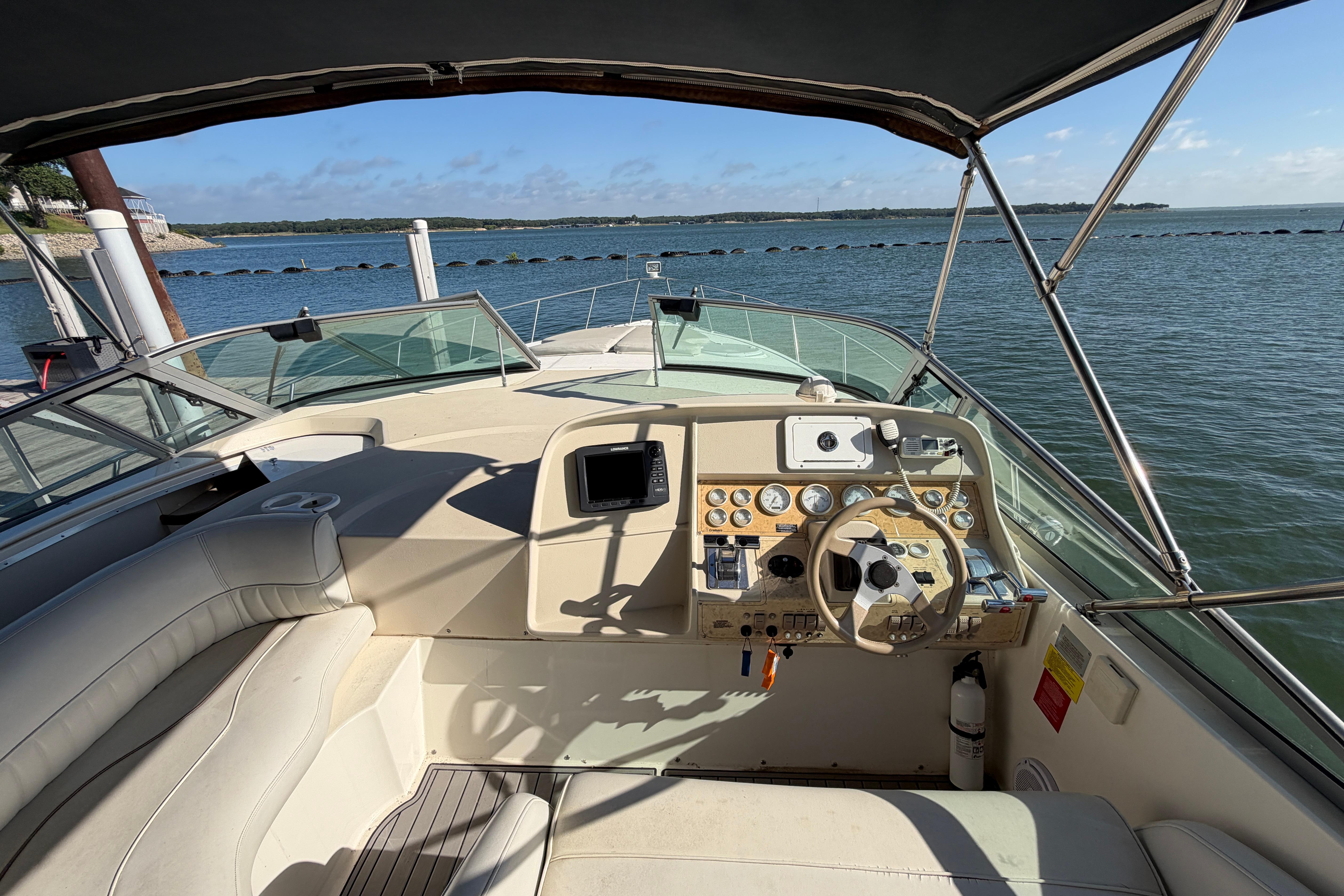 1997 Cruisers 3575 yacht cockpit with steering wheel, gauges, and lake view.