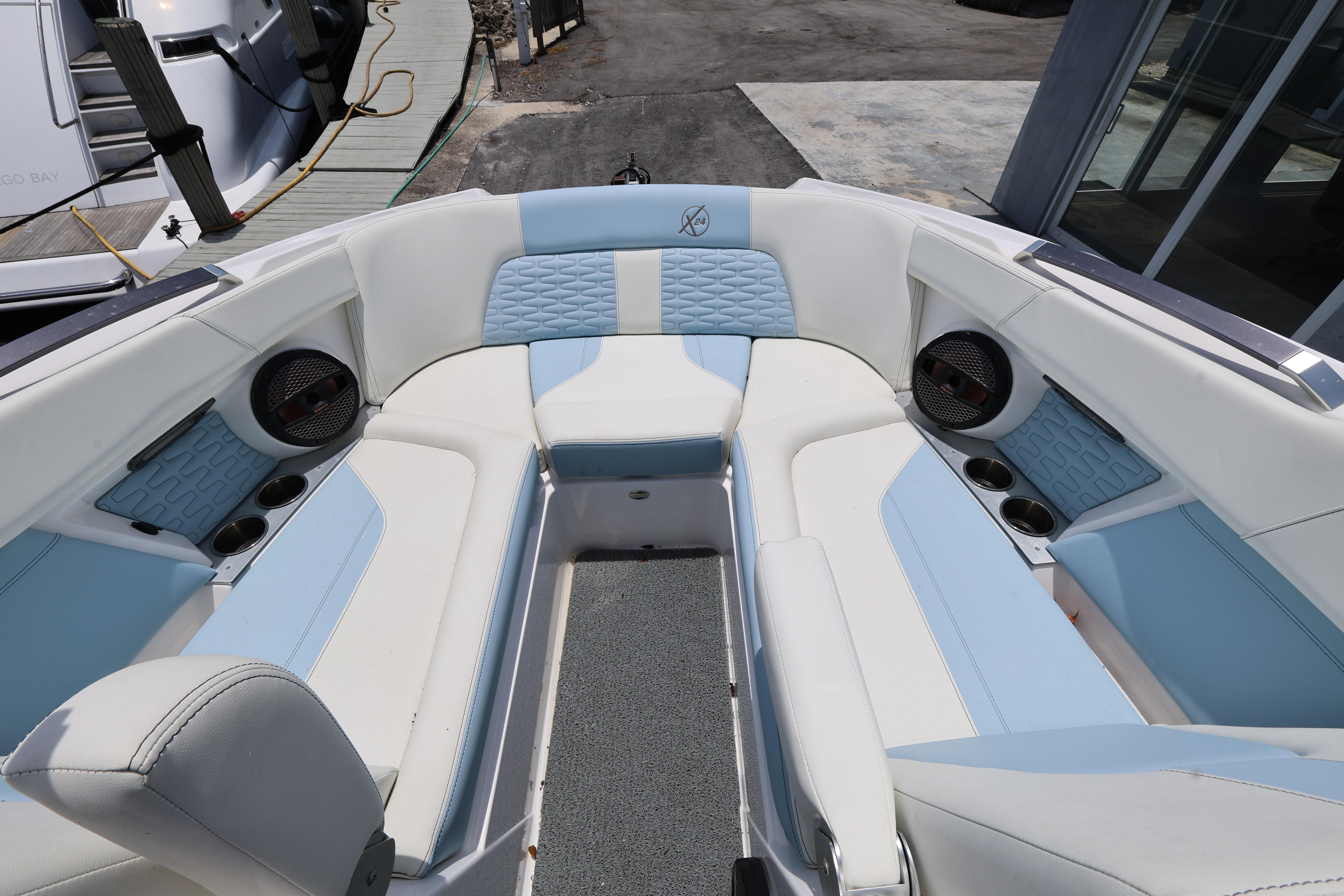 2023 MasterCraft X24 boat interior with white and blue seating, cup holders, and speakers.