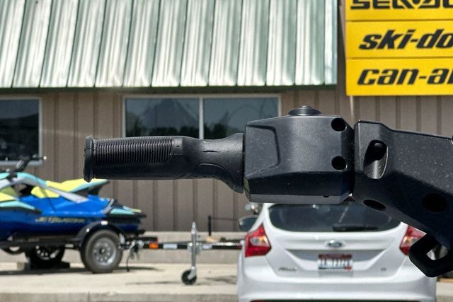 Close-up of a black jet ski handlebar in front of a building with signs.